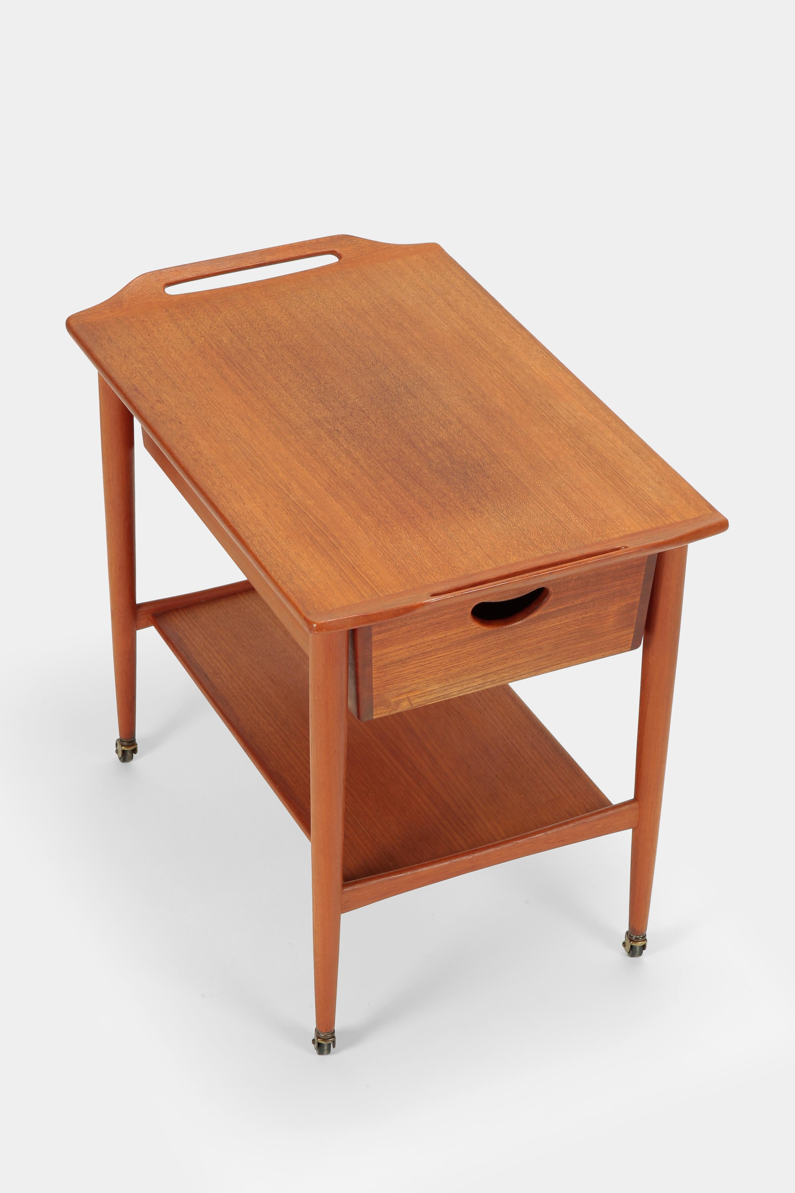 Attributed to Poul Hundevad serving trolley manufactured in the 1950s in Denmark. Serving trolley with solid teak parts. Under the veneered table top there is a spacious drawer that can be pulled out from both sides. Danish craftsmanship and design