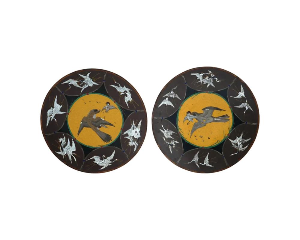 A pair of identical antique Japanese copper serving plates with cloisonne enamel design. Late Meiji period, ca. 1895. Round footed pieces. Black ground color. The piece is decorated with a crane and eagle bird motif. Presumably a work of Hayashi