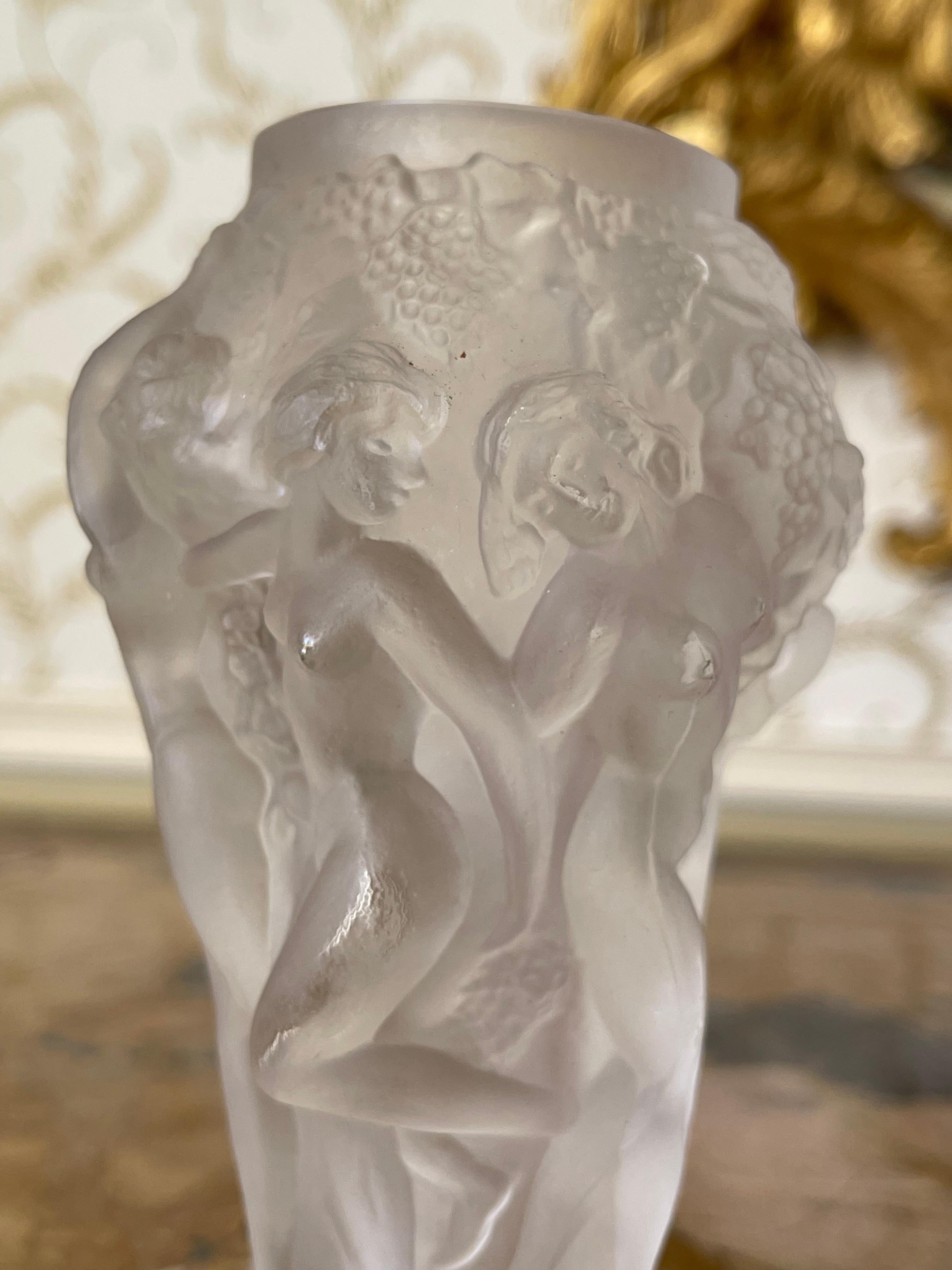 Small pressed and satin molded glass vase with relief decoration of a round of bacchantes with vine branches. The base is circular with canted sides. It is not signed and in very good condition.