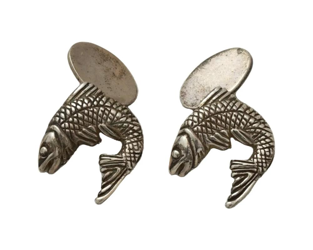 Une paire de boutons de manchette en argent sterling, attribués à Stephen Webster. Les boutons de manchette ont la forme de poissons, gravés de motifs détaillés. Le poinçon standard en argent sterling et la marque W sont apposés au dos de l'objet.