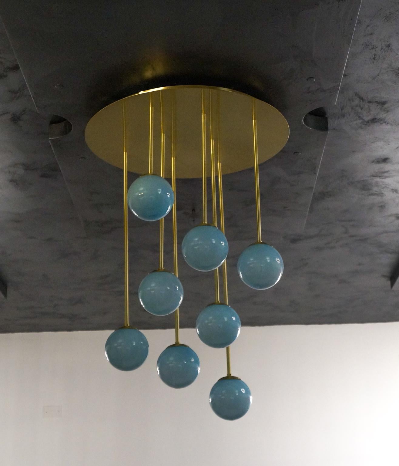 This is a modern and particular chandelier, perfect for a Minimalist and spacious environment that will surely give a touch of style to the room.
The frame supports 8 aquamarine or white glass spheres that seem suspended and emit a very soft and