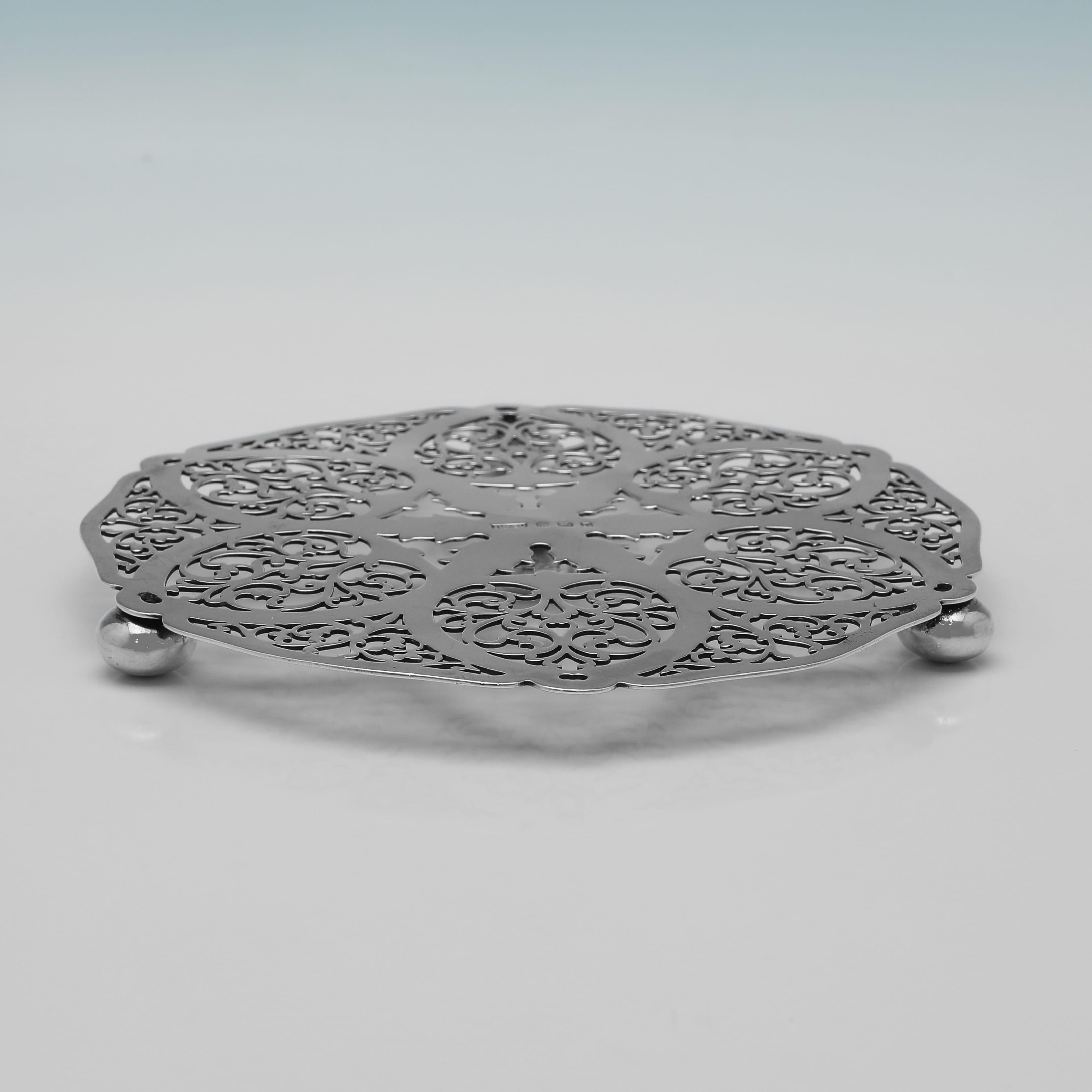 Poinçonné à Birmingham en 1930 par Roberts & Dore, ce joli dessous-de-plat en argent sterling repose sur trois pieds sphériques et présente une décoration géométrique percée. Le dessous-de-plat mesure 1,5 cm de haut pour 15 cm de diamètre et pèse