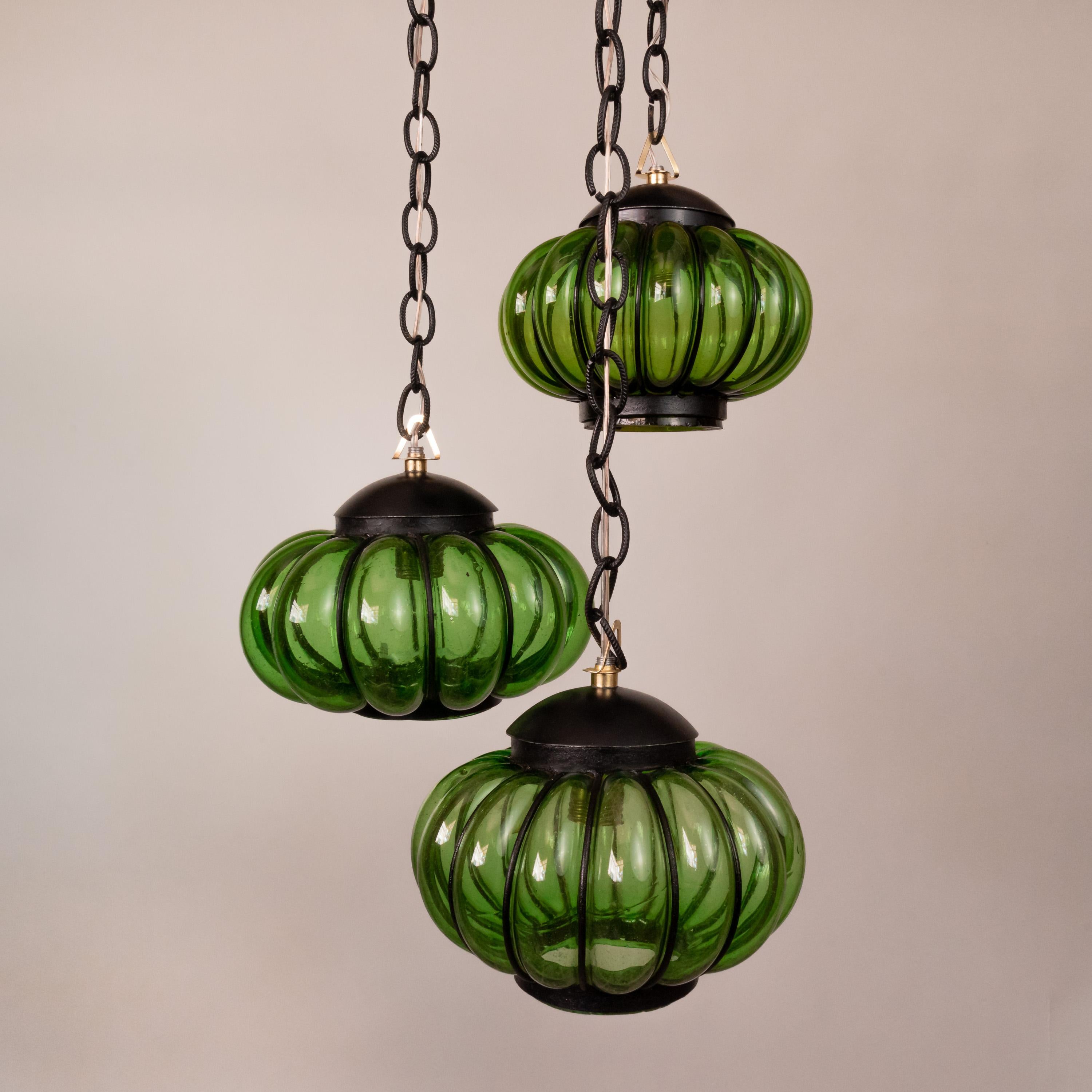 Beautiful chandelier assembled with three original Feders pumpkin-shaped shades of blown green glass trapped in wrought iron painted black. Each sphere hangs from a black chain and was set at a different height to create a visually appealing