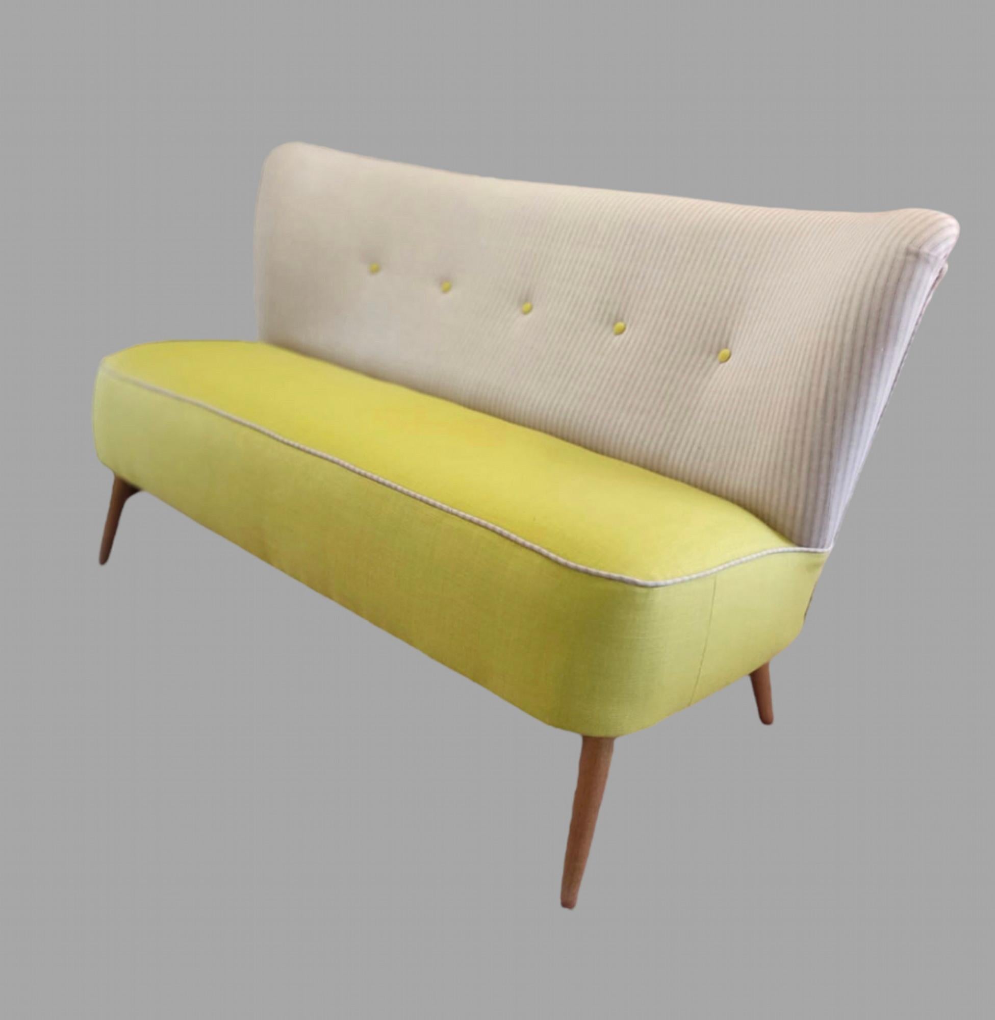 This is an attractive Danish sofa with a curved detail on stylish narrow  beech legs reupholstered in a yellow linen to the seat and pink linen tick to back and sides, double piped in the ticking with contrast yellow buttons.