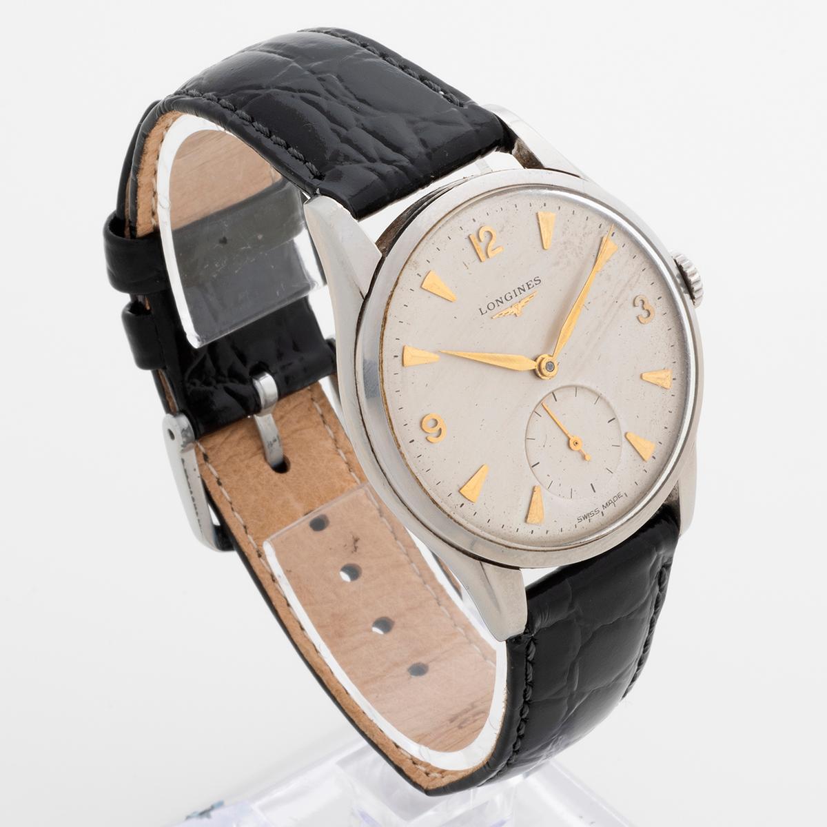 Our attractive and original manually wound Longines features a lightly patinated silver dial with rare gilt arabic and dagger hands and subdial with seconds. The crown is signed Longines. A larger than average case for its era, measuring 34mm