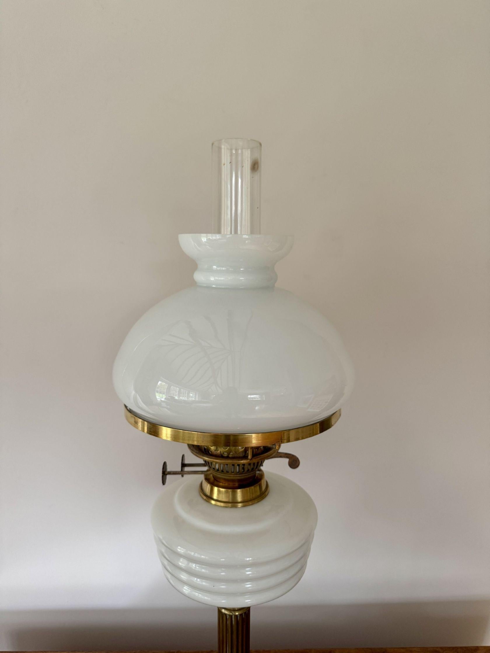 Attrayante lampe à huile ancienne de style édouardien avec son abat-jour en verre blanc d'origine, un double brûleur en laiton au-dessus d'un réservoir en verre blanc soutenu par une colonne en laiton reposant sur une base circulaire en laiton