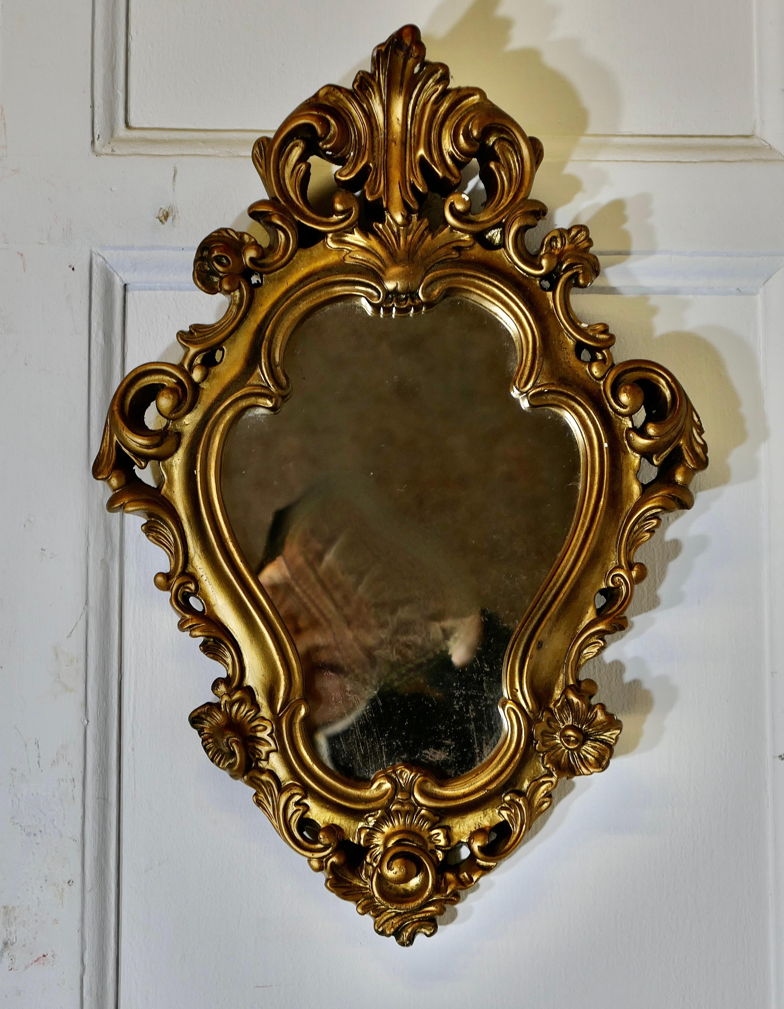 Atractivo Espejo de Pared Pequeño Dorado de Estilo Rococó

El Espejo tiene una forma inusual, tiene un elaborado marco ancho de yeso dorado de estilo French Rococo, hay abundante decoración de conchas y hojas de acanto por todo el marco
Un