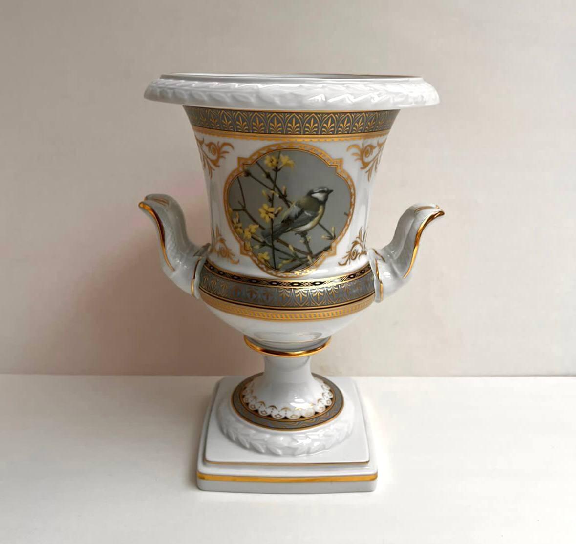 Attraktive Vintage-Vase mit Griffen von Kaiser, Pavillon, Deutschland.

Balusterförmige Vase aus hochwertigem weißem Porzellan mit Vergoldung und grüner Farbe, verziert mit einem Gemälde, das einen Vogel auf einem Ast darstellt.

Unter der Vase