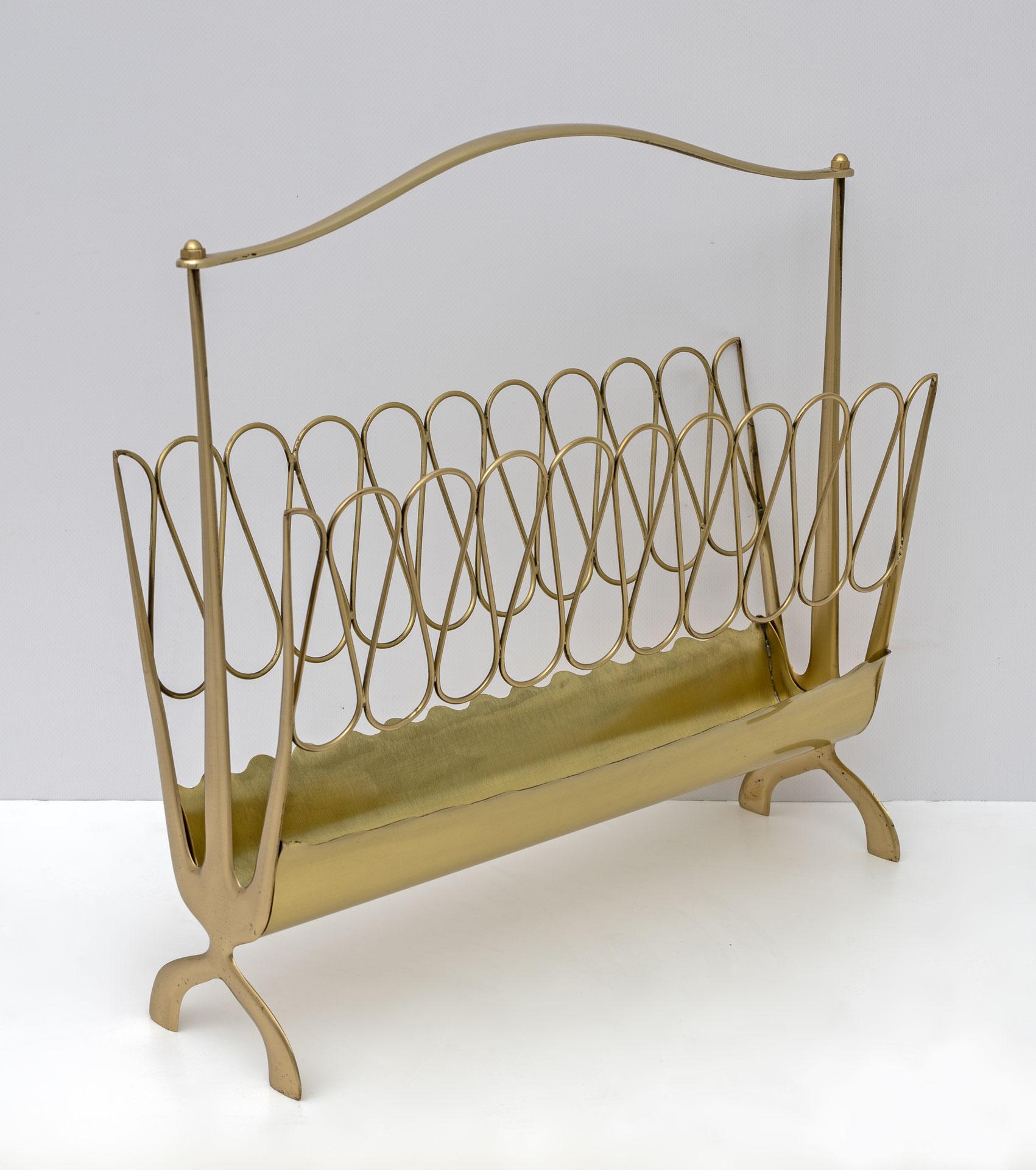 An elegant Mid-Century modern brass magazine rack attributed to Osvaldo Borsani with curved sides and carrying handle resting on two V-shaped feet, professionally polished and will not tarnish.