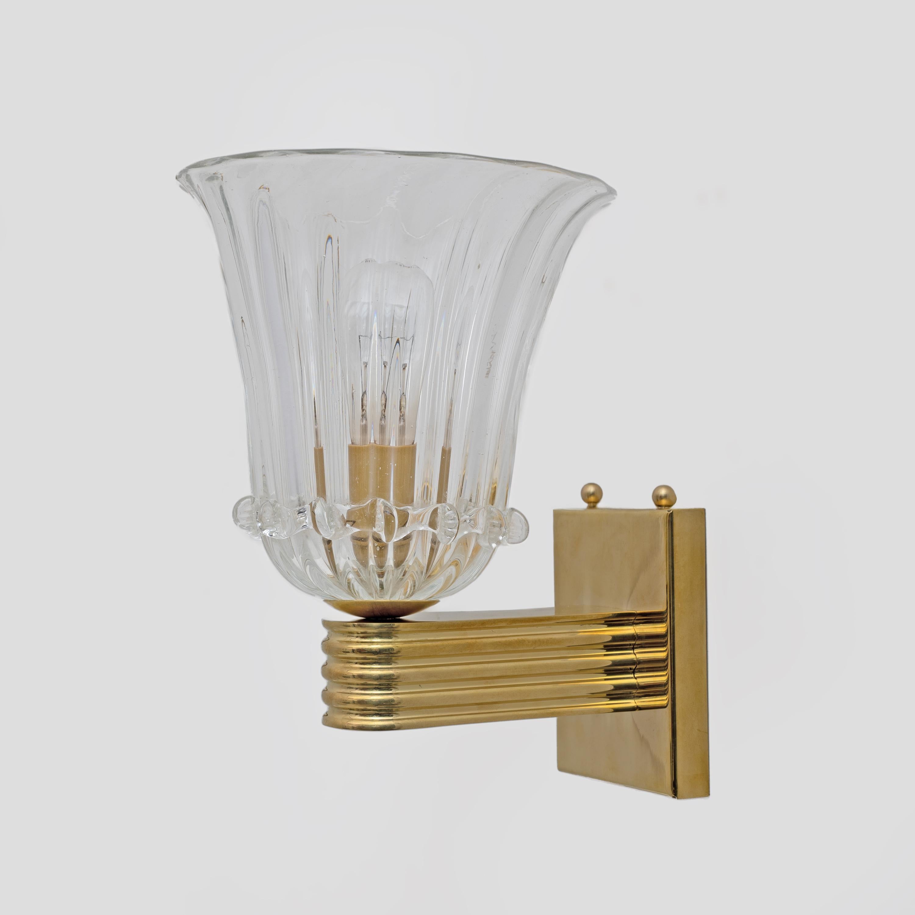 Cette fabuleuse paire d'appliques Art déco en verre de Murano a été entièrement réalisée à la main. Verre soufflé à la bouche, les bords sont joliment festonnés. Ils sont posés sur un élégant socle en laiton texturé. Ils sont extrêmement décoratifs