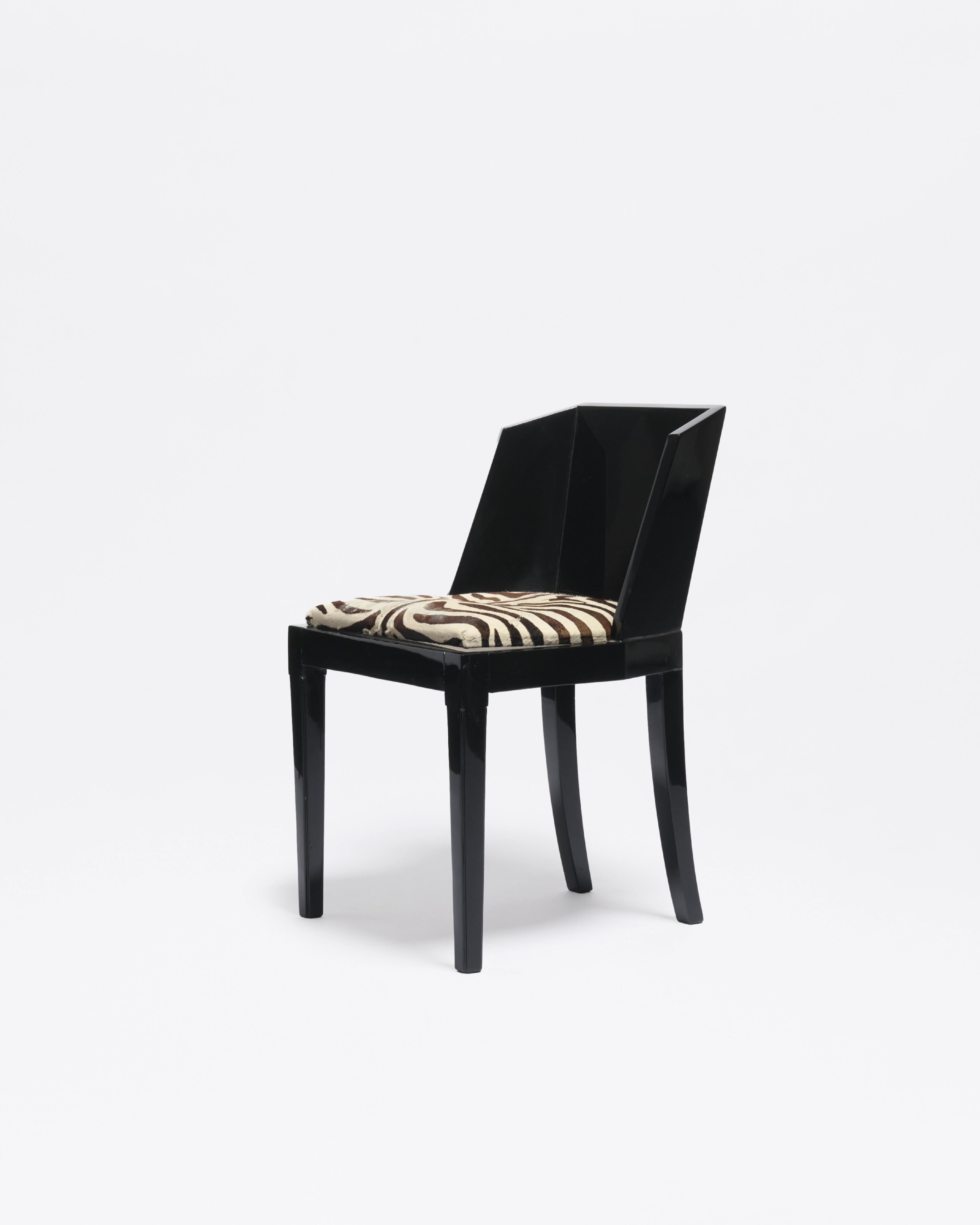 Set of six Art Deco chairs in black lacquered wood with sharply faceted backs and zebra-patterned seats. The design shows strong affinity with Jean Dunand’s sculptural lacquer work from the 1920s. While unsigned and unstamped, the confident