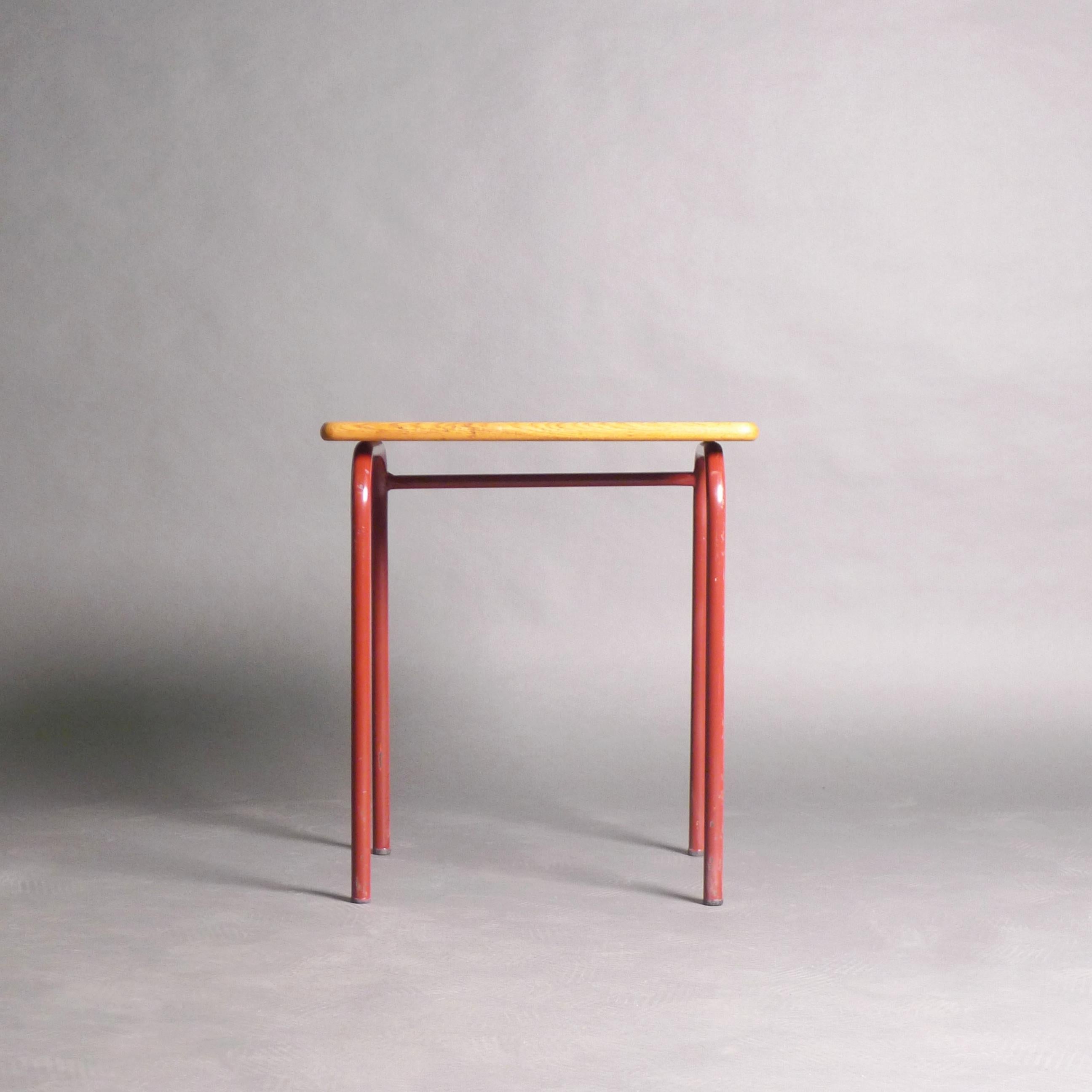 Delightful child's school desk or writing table, attributed to Jean Prouvé, 1950s.

The rectangular oak top with indented pen rest on red enamelled metal curved legs ending in rubber caps of the same type found on Prouvé standard chairs.  Originally