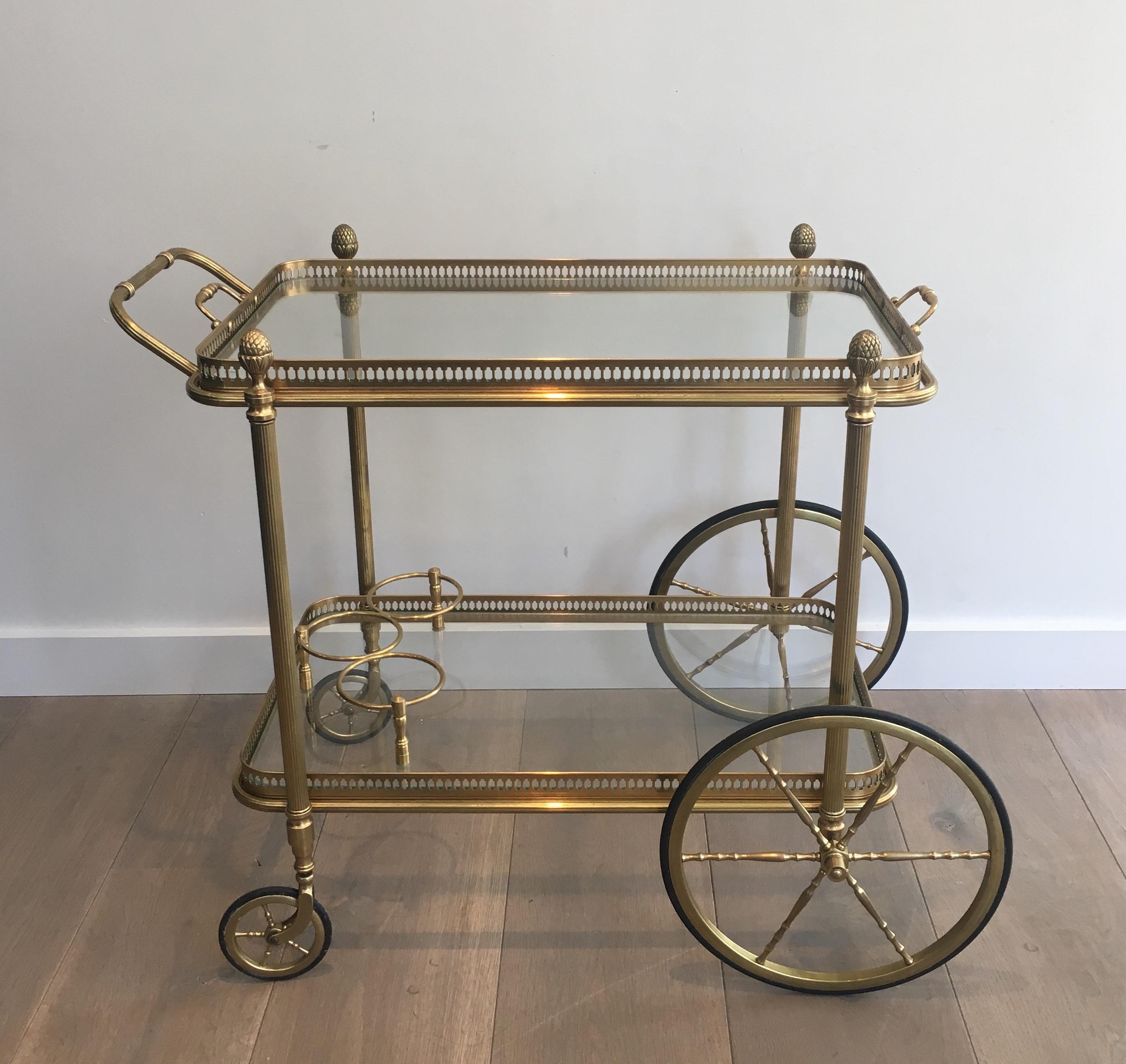 This neoclassical bar cart is made of brass with clear glass removable trays surrounded by a brass gallery. This drinks trolley is attributed to famous french designer Maison Bagués, circa 1940