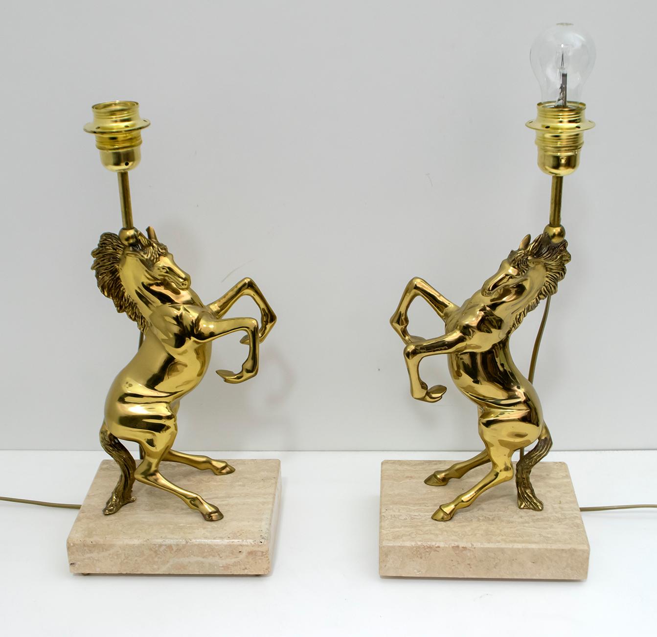 This pair of French lamps were produced in the 1970s and attributed to Maison Charles.
The lamps, two polished brass horses resting on a travertine base and brass feet.