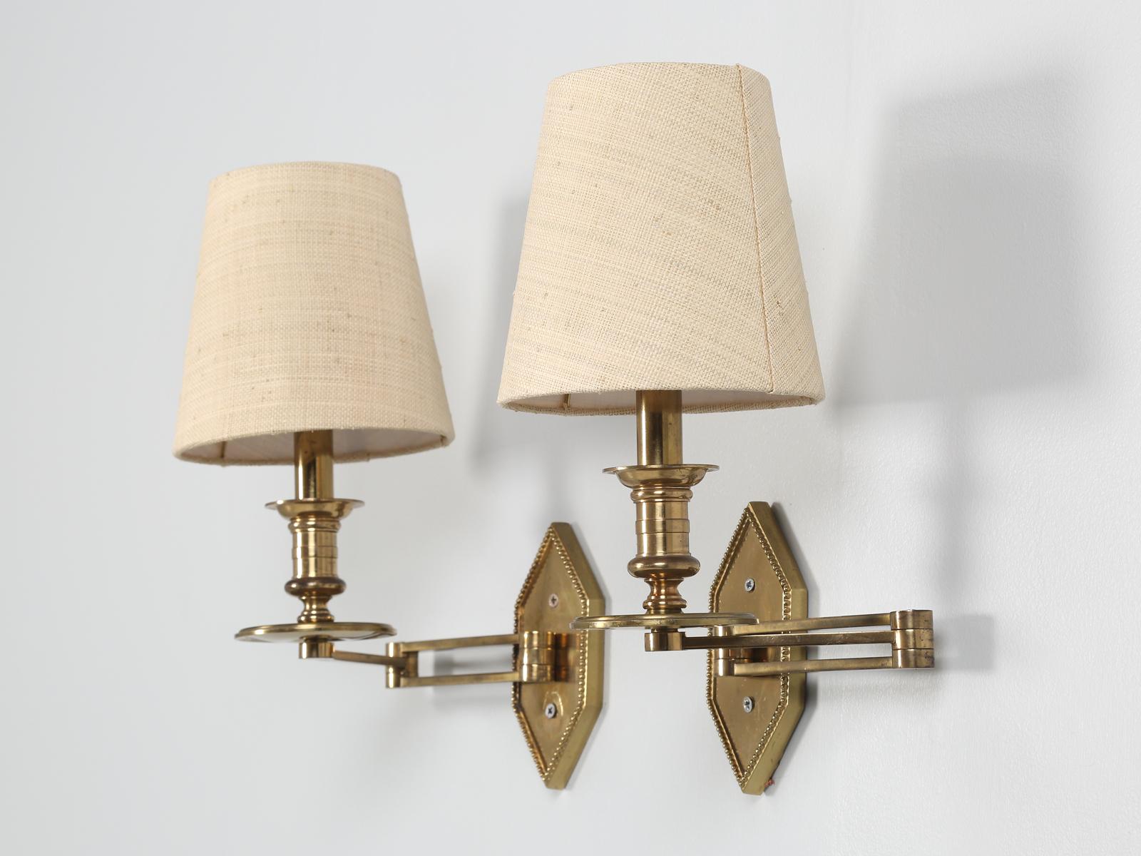 Attributed to Maison Jansen, pair of articulated or swing arm brass sconces in nice original condition. We believe that the brass sconces were made in the late 40's or 50's and are idea flanking a bed. 

**Nice patina throughout. Back plates are
