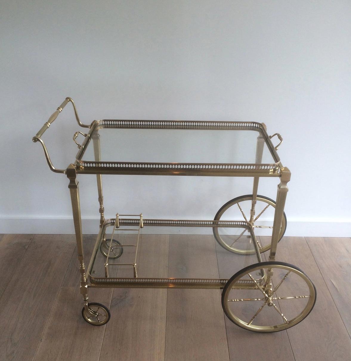 This neoclassical bar cart is made of brass with glass shelves. The quality of this drinks trolley is really good. It has fluted legs, large wheels in front and small ones on the back and has two removable trays. This is a French work, attributed to
