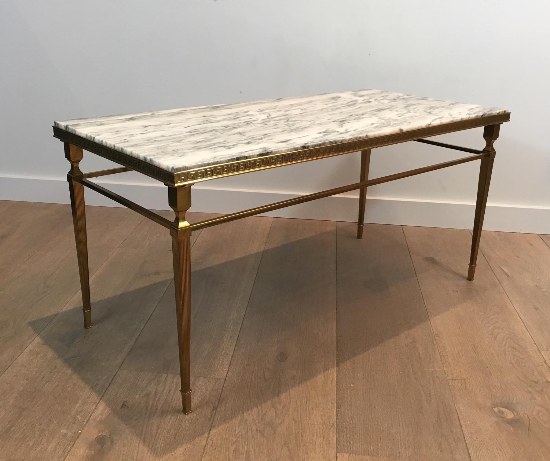 This neoclassical coffee table is made of brass with Greek keys decor and a white and grey marble top. This cocktail table is a French work, attributed to famous Maison Jansen, circa 1940.