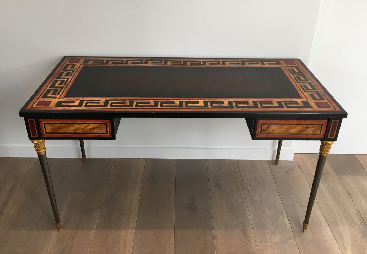 Attributed to Maison Jansen. This beautiful neoclassical desk or drawer table is made of a lacquered top with Greek keys decor and brushed steel and gold gilt bronze feet. The decor is a bit used on some parts as shown on the attached pictures,
