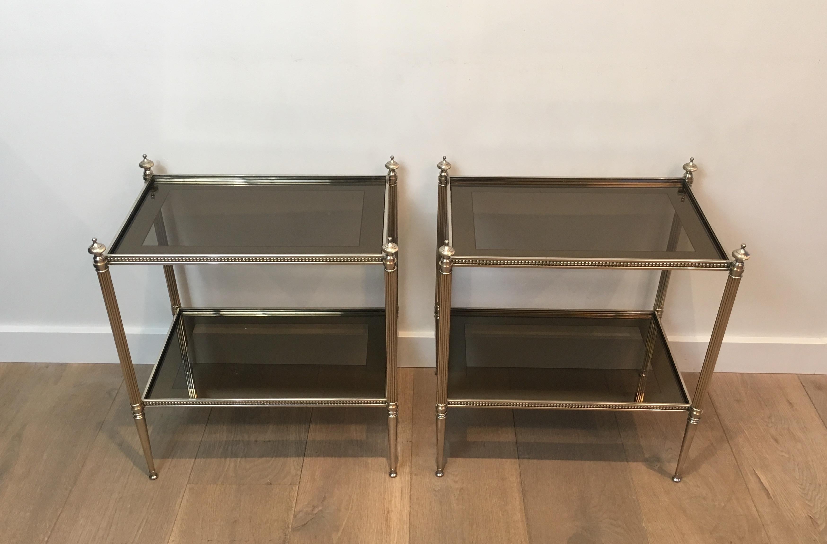 This very nice pair of neoclassical style side tables is made of silver plated with bronze glass shelves surrounded by a silver-mirrored line. This is a very nice French work, attributed to Maison Jansen, circa 1960.
 