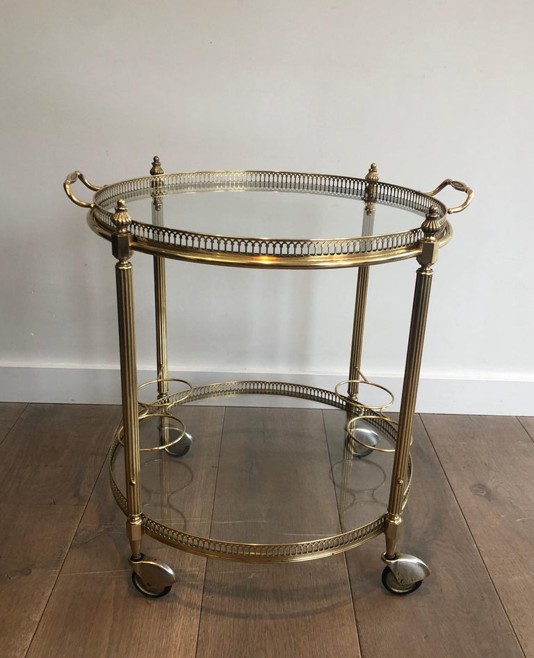 This nice neoclassical round bar cart is made of brass and glass with a top removable tray and a three bottles holder on each side. This drinks trolley attributed to famous French designer Maison Jansen, circa 1940.