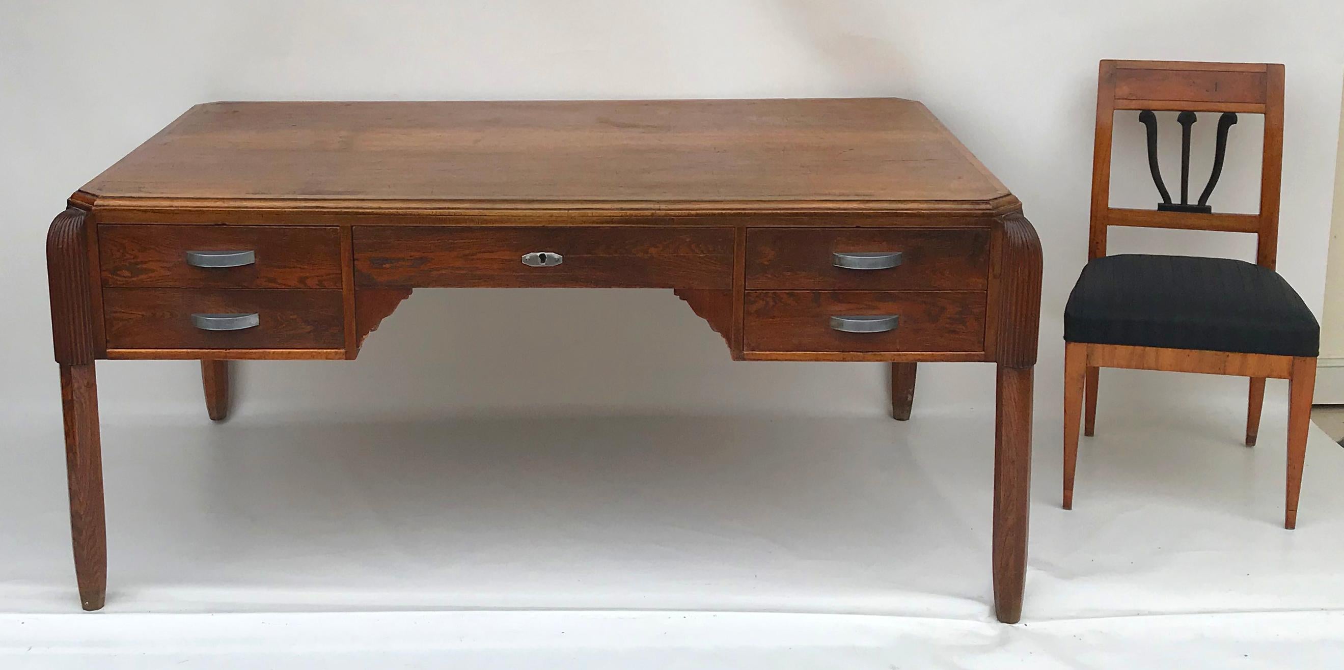 Attributed to Paul Follot, large Art Déco desk, 1920s. Made of walnut and oak. 

Round, caneled legs attached to the body, front with five drawers and original handles and locks, recessed top. The desk captivates with its sleek design. It will be
