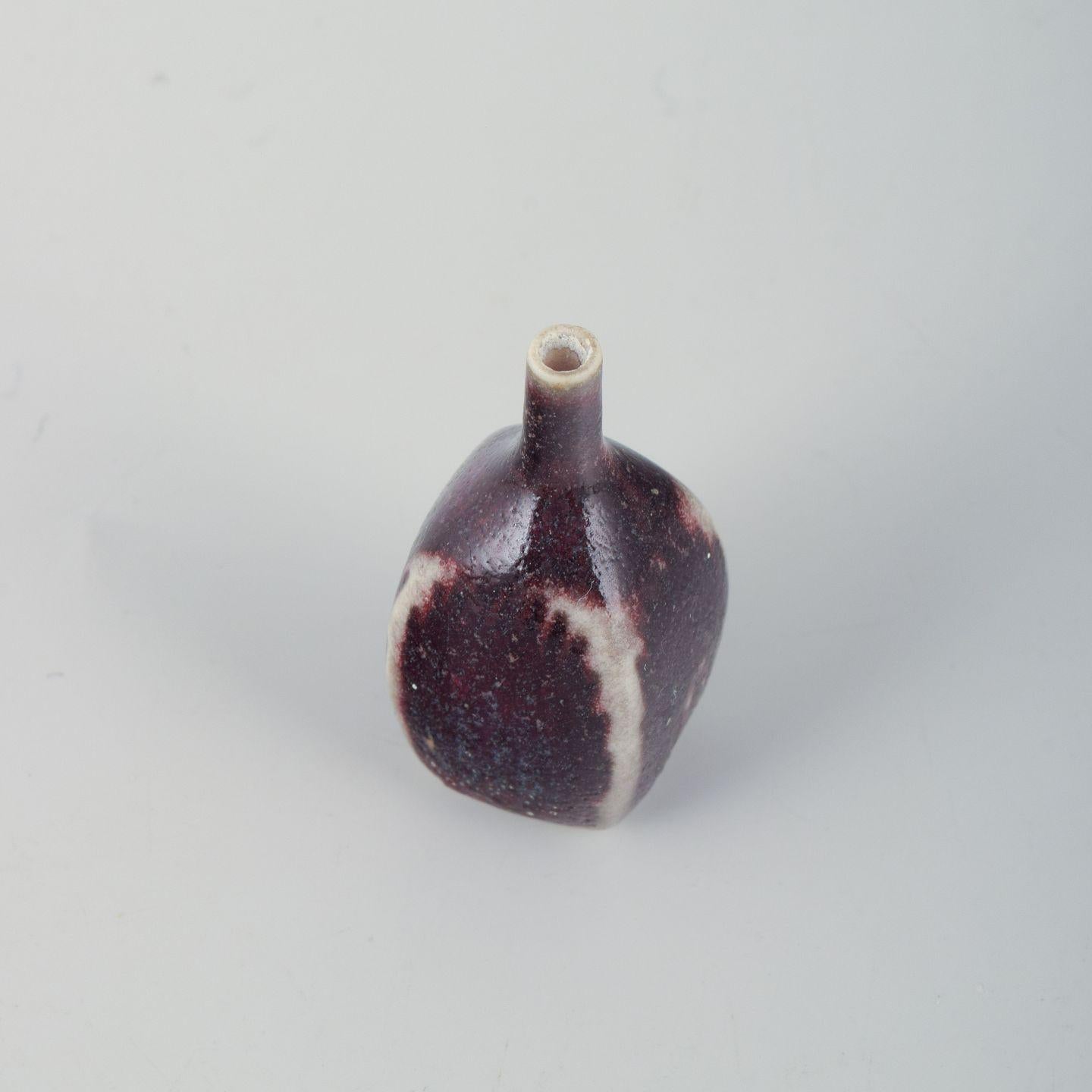 Attribué à Stig Lindberg, vase miniature en grès, pour Gustavsberg Studio.
Vase miniature en grès magnifiquement émaillé en rouge profond avec des zones de contraste plus claires et de subtiles variations de surface. 
La forme simple et organique