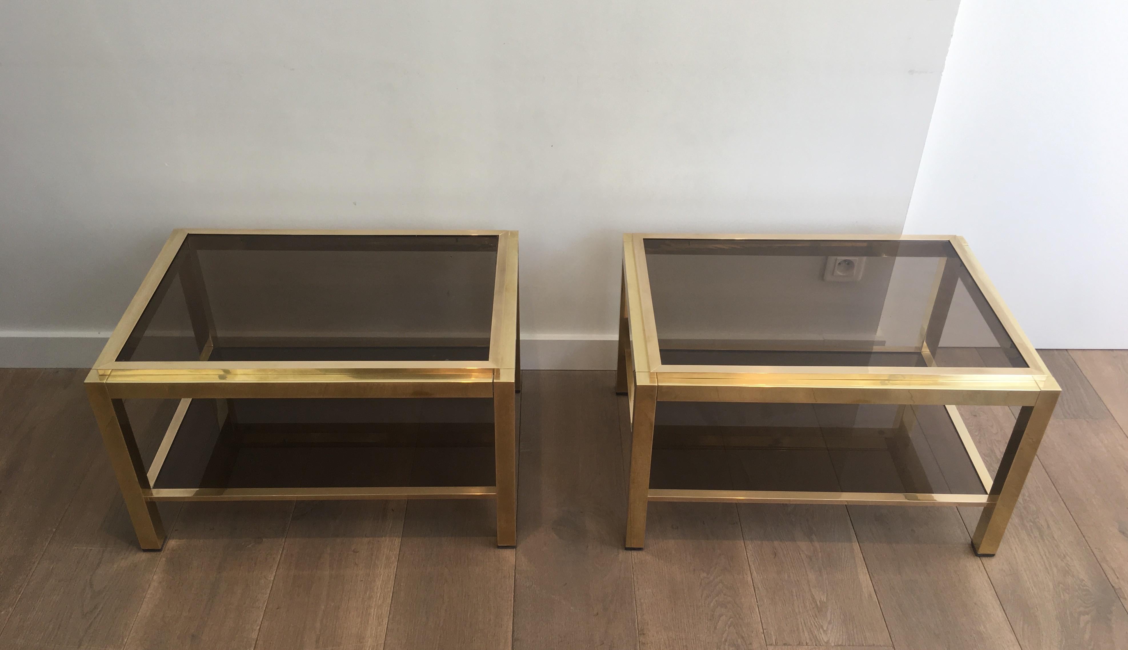 This beautiful pair of side tables are all made of brass with bronzed glass shelves. The top glass shelves are inserted in a brass frame constituted of 4 elements. This is a model attributed to famous designer Willy Rizzo, circa 1970.