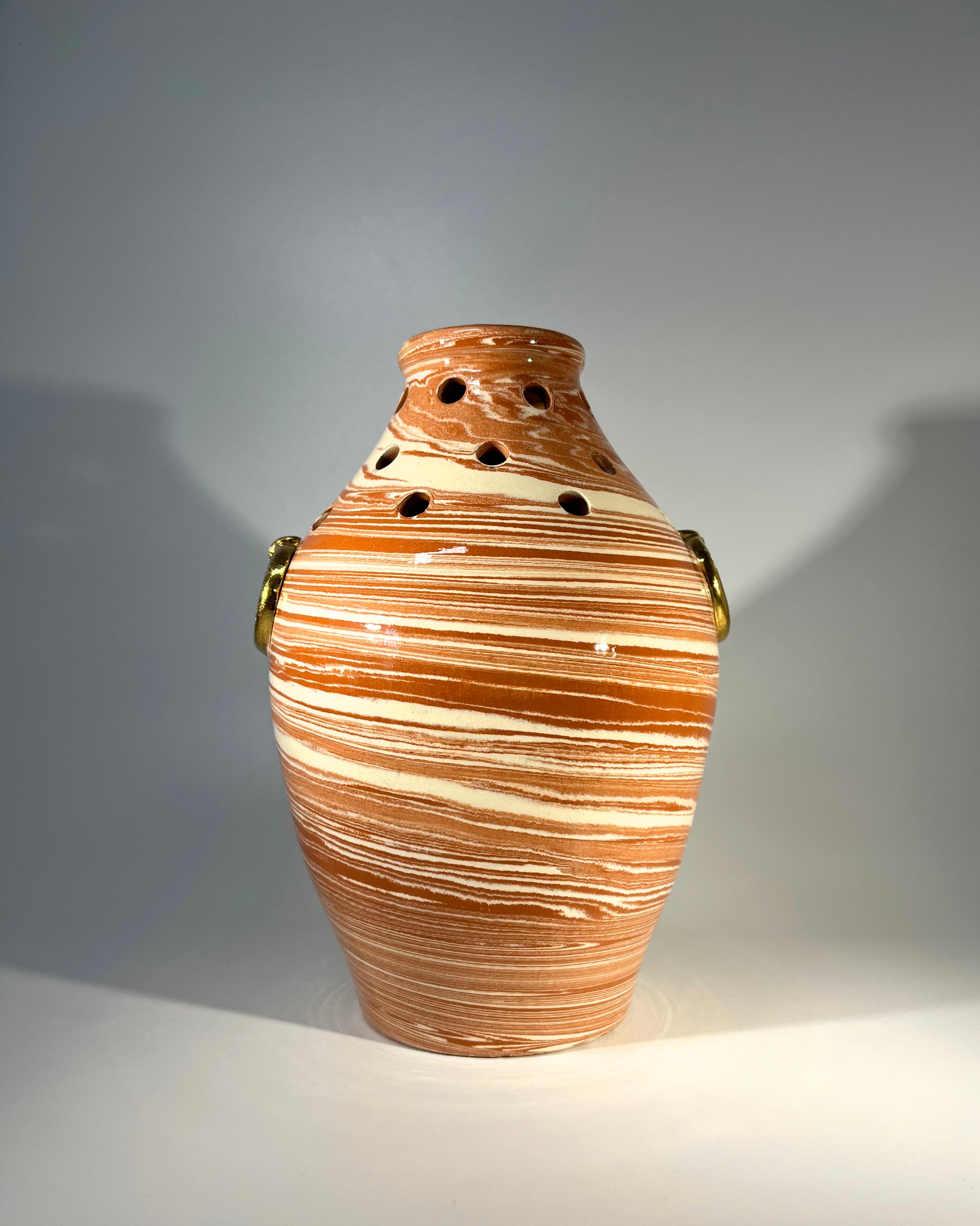 Vase urne en céramique percée et émaillée de Vallauris, France, d'une grande originalité.
Décorée à la main pour simuler les marbrures et ornée de deux faux anneaux en céramique dorée. 
Circa 1970's
Signé Vallauris
Hauteur 8 pouces, Diamètre 6.5