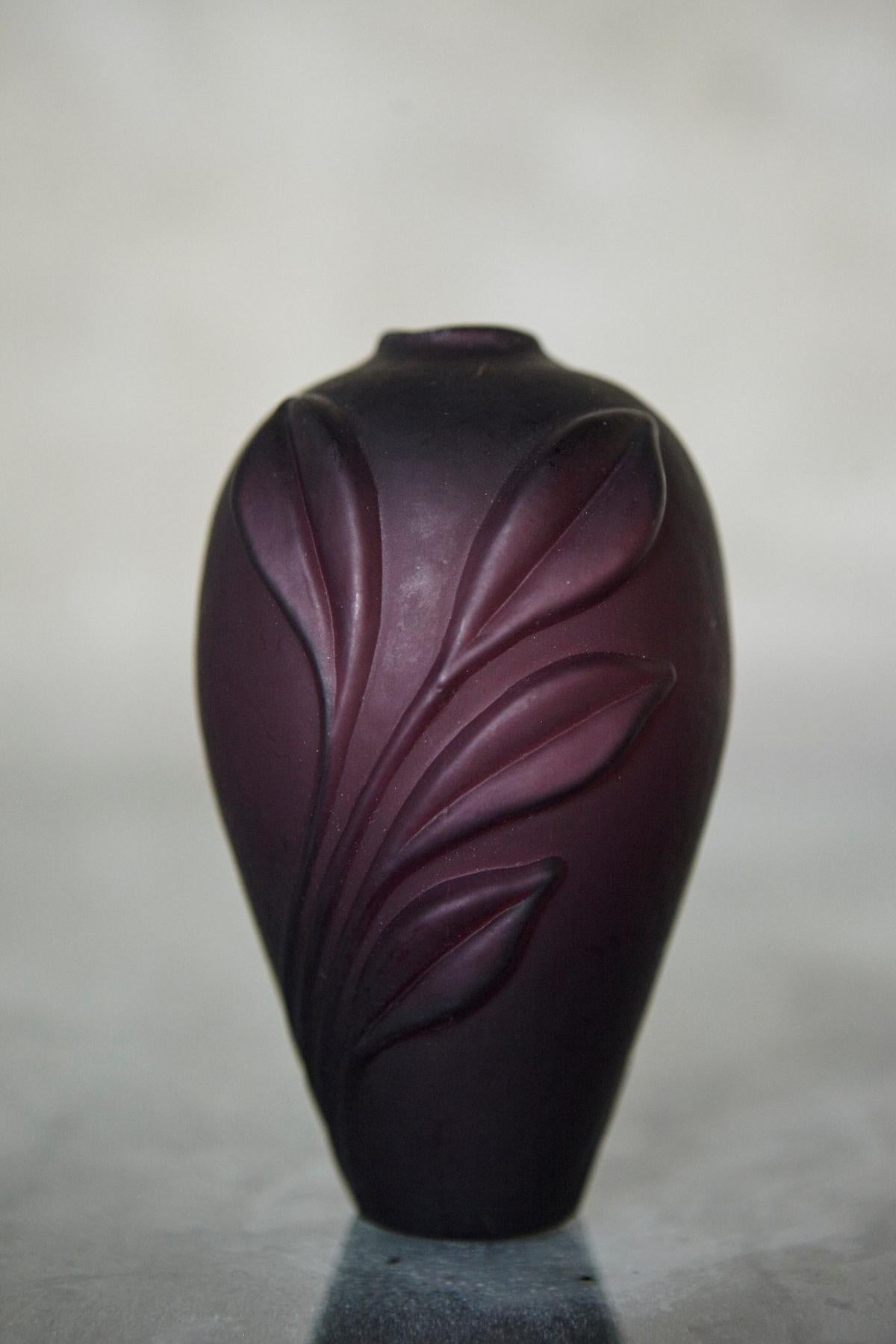 This aubergine matte glass bud vase offers a clean, sculptural profile suited to contemporary interiors. Designed for a single stem or small arrangement, the vase features a slender ovoid body with a subtle raised leaf motif that adds quiet relief