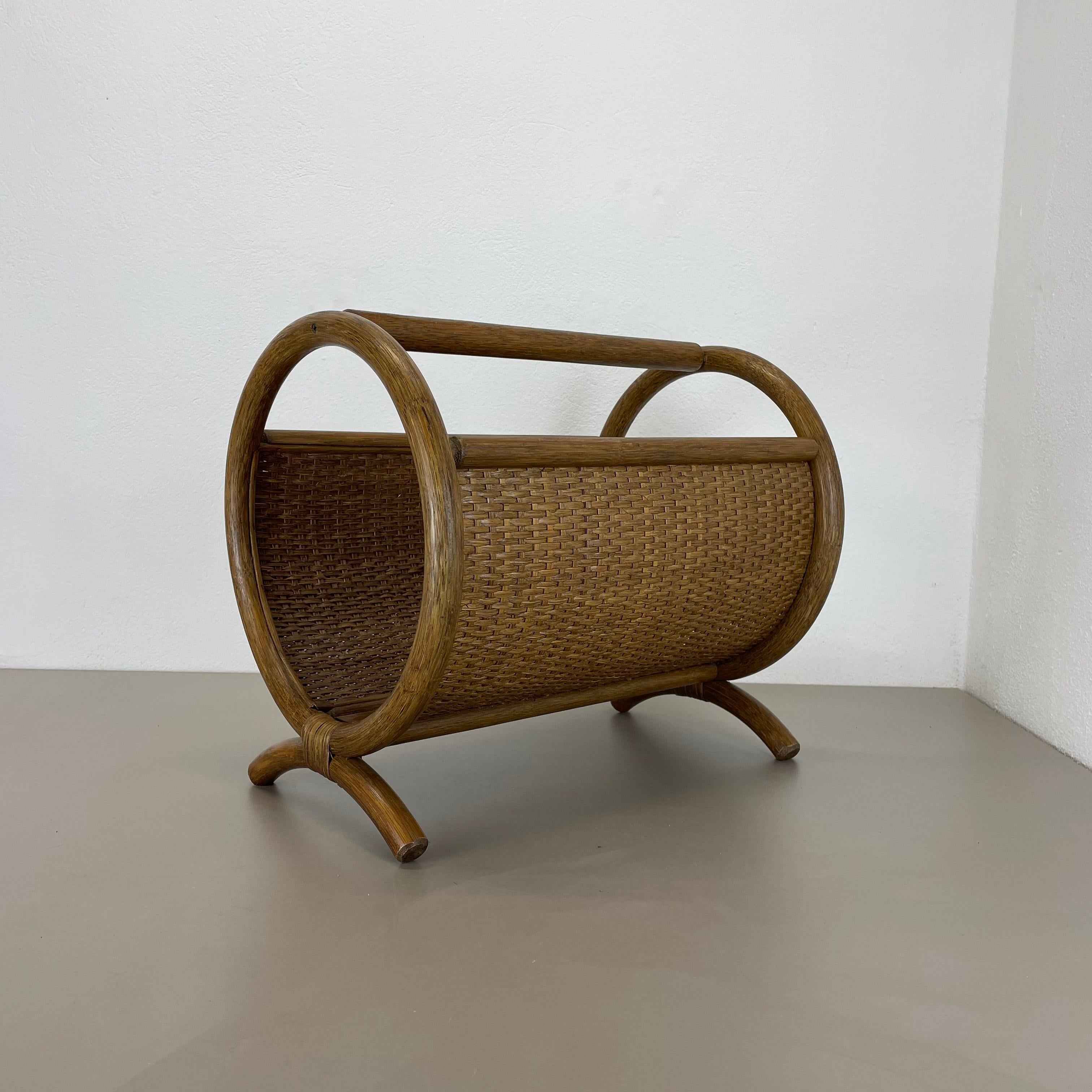 Article: magazine holder stand element
Origin: France
Age: 1980s.
This original vintage Bauhaus style magazine holder stand was produced in the 1980s in France. It is made of natural wood rattan in a round formed shape and at the top a handle