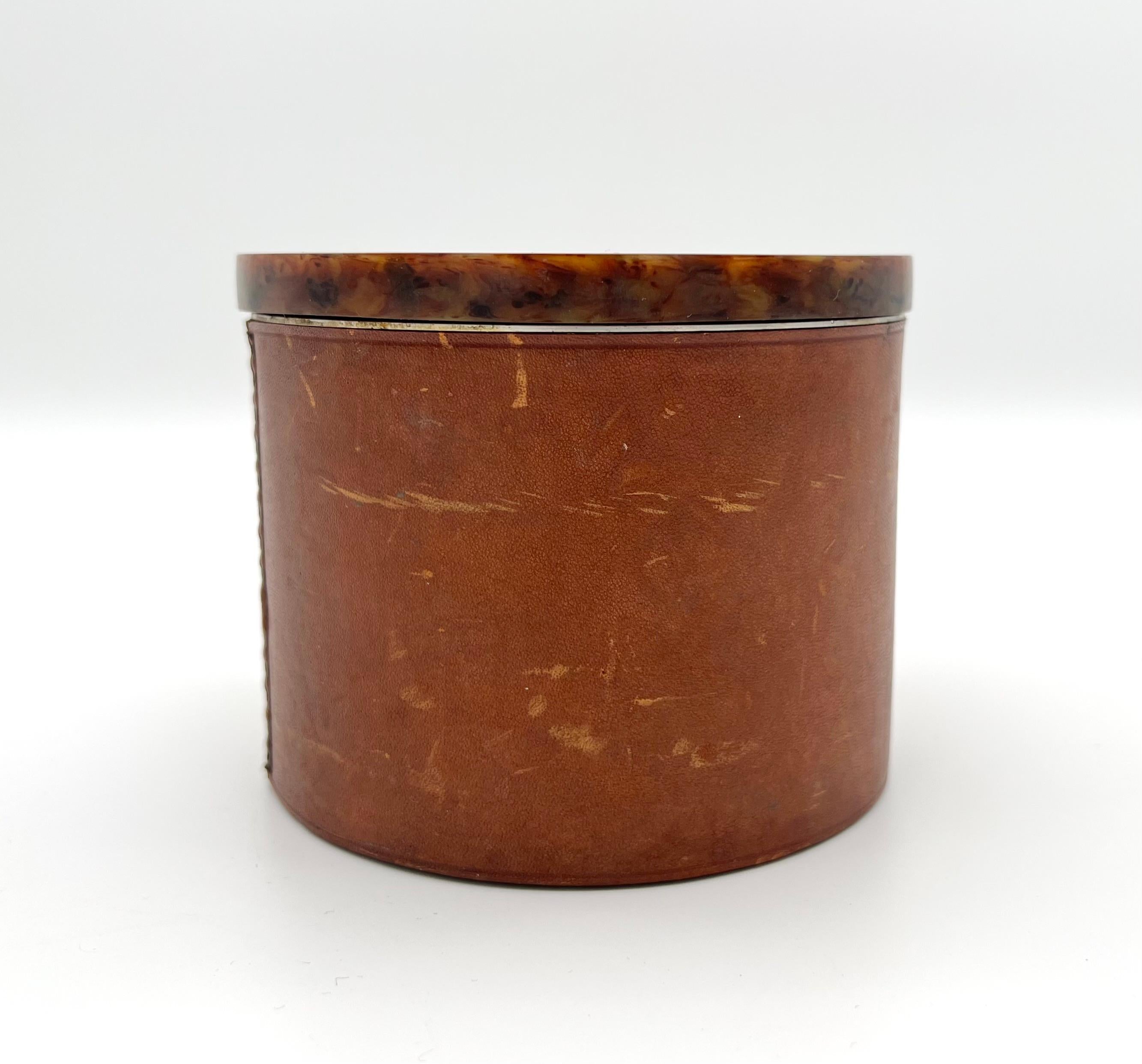 Aubock tobacco box, 1950s
Made of aluminum, with a leather wrapp sleeve and a bakelite lid.

Listed in the catalog 