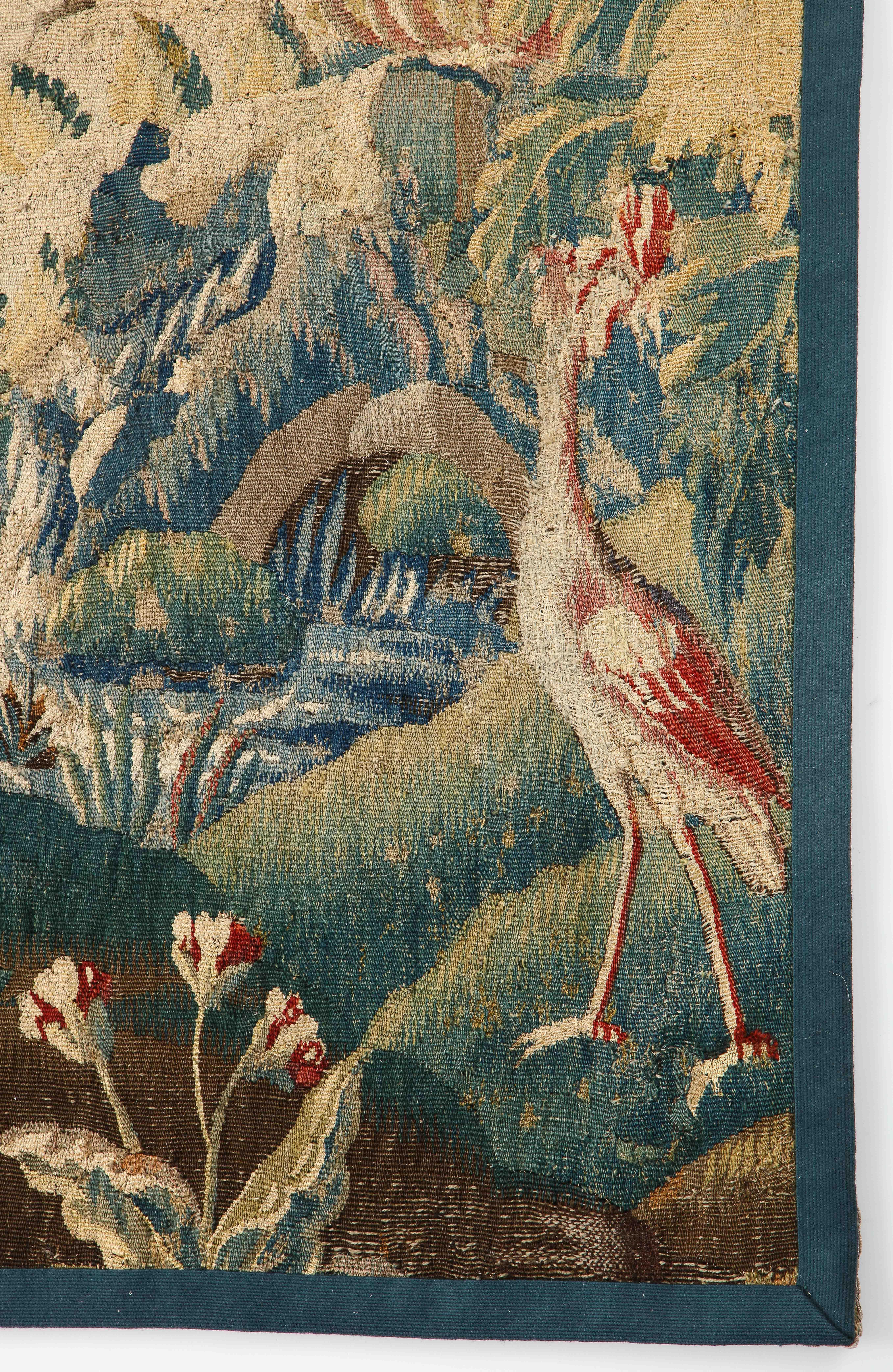 An 18th century verdure Aubusson tapestry handwoven in wool. This pastoral scene is composed of stylized trees, flowering plants and birds near a body of water surrounded by hills. This is one of two panels in our collection. The workmanship of this