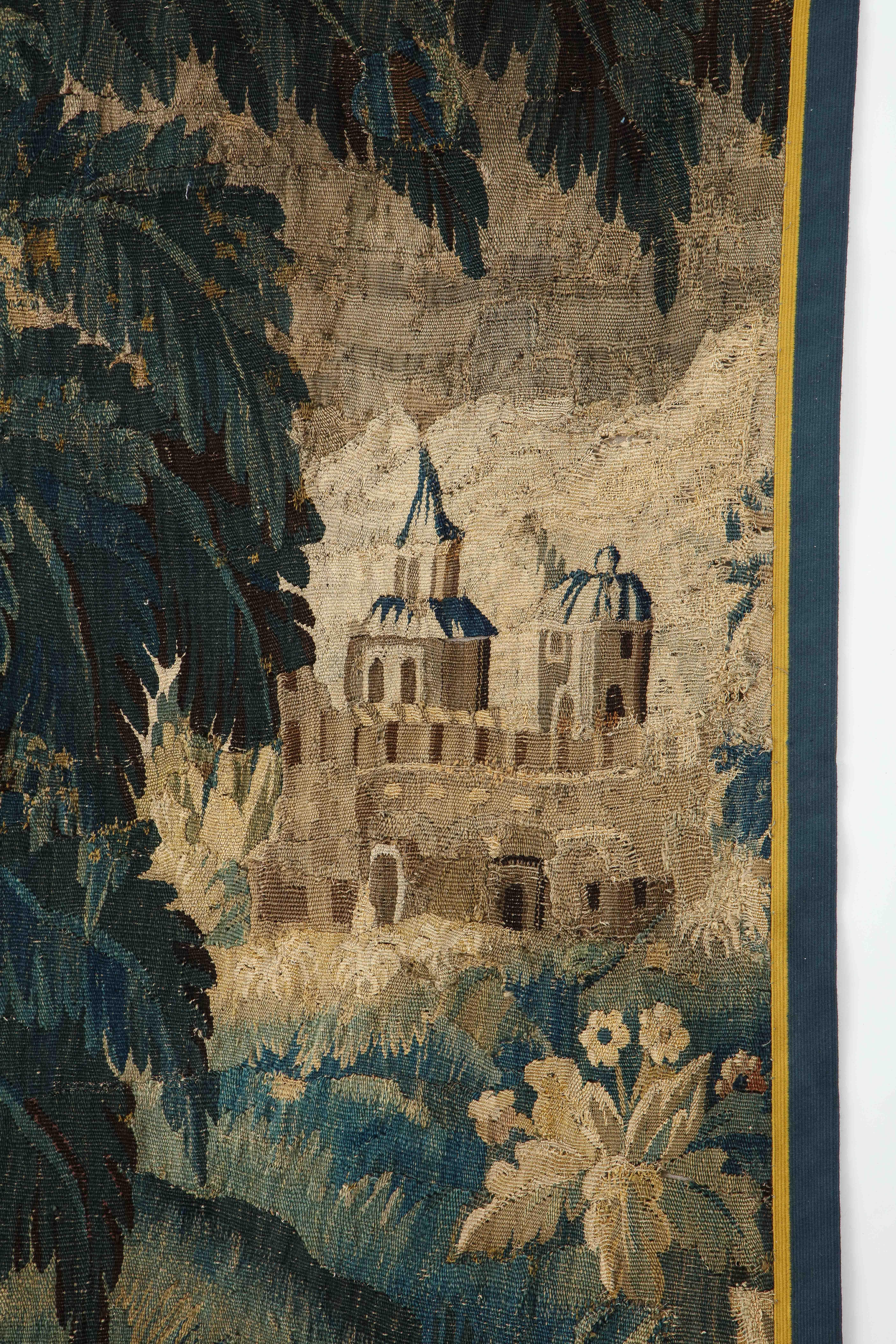 An 18th century verdure Aubusson tapestry handwoven in wool. This scenic landscape depicts a charming scene with a castle in the background and. large trees and flowering plants along side a feeding heron in the foreground. This is one of two panels