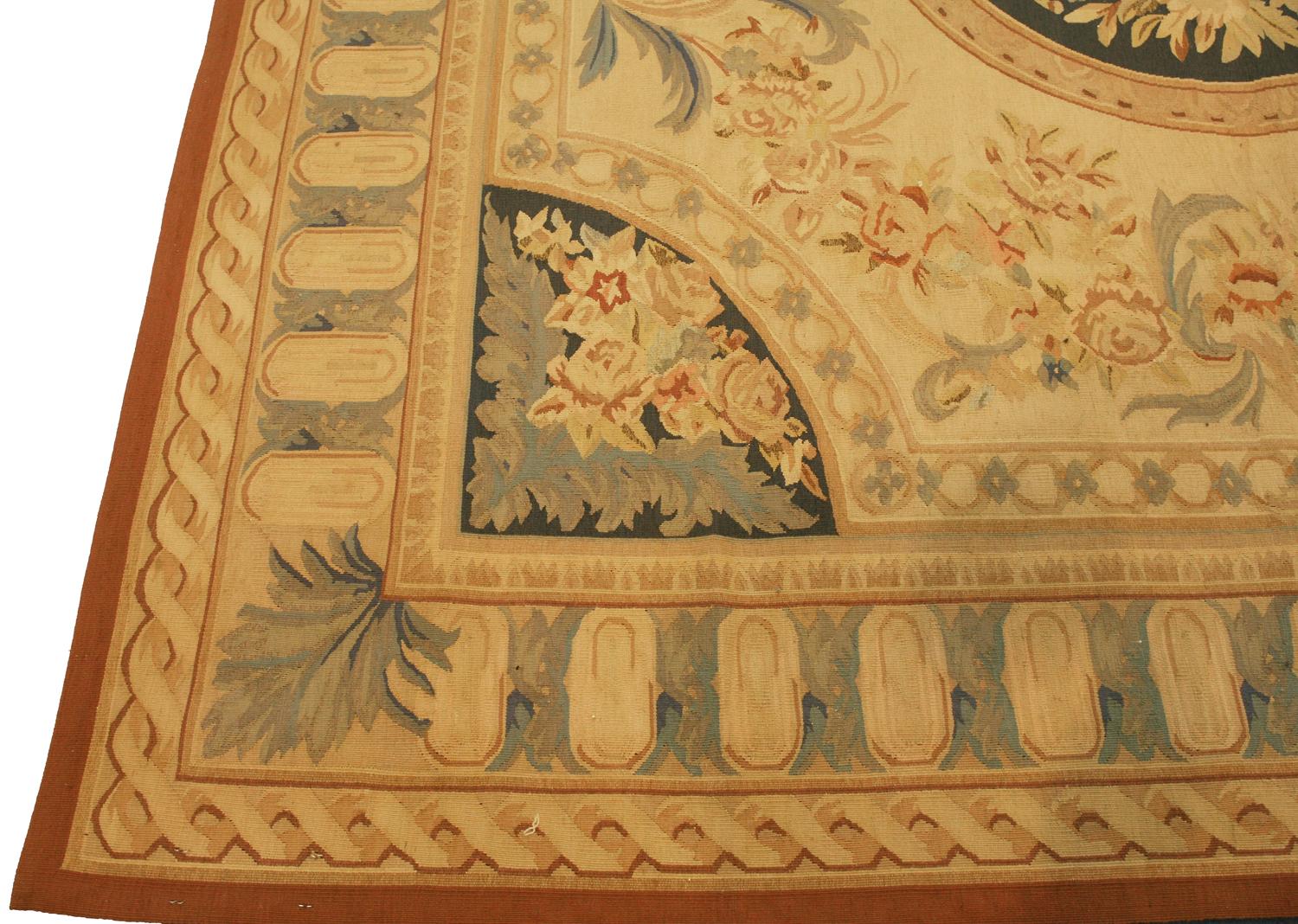 Questo tappeto Aubusson a trama piatta è una bellissima aggiunta a qualsiasi stanza. Un medaglione circolare incastonato su uno sfondo scuro con eleganti ornamenti floreali fluttua maestoso su questo aubusson in stile classico francese. Questo