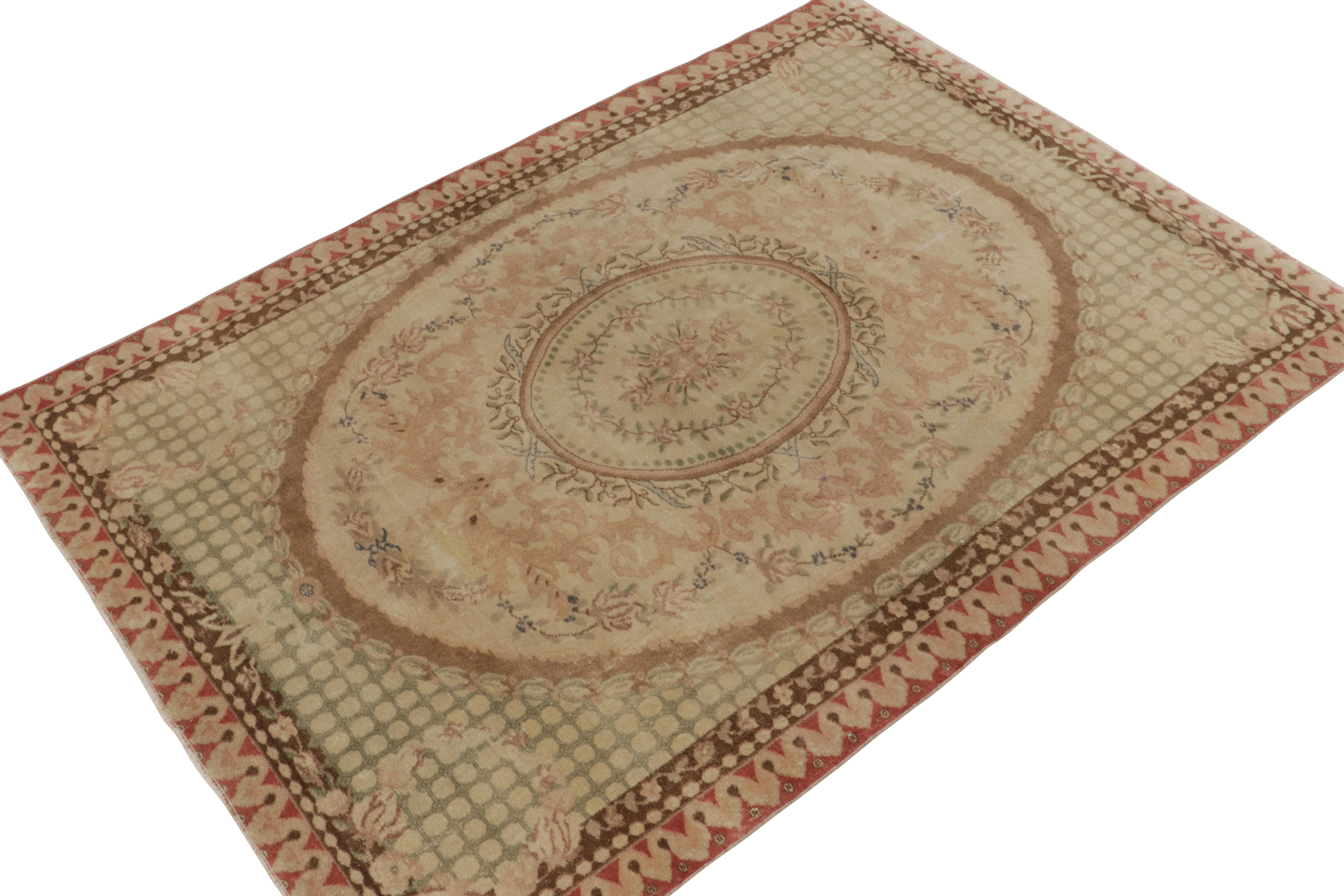 Originating from Turkey circa 1950-1960, this vintage mid-century rug draws unique inspiration from 18th-century Aubussons—a renowned European style. This particular design marries elegant cartouche medallions and floral patterns in pink, green &