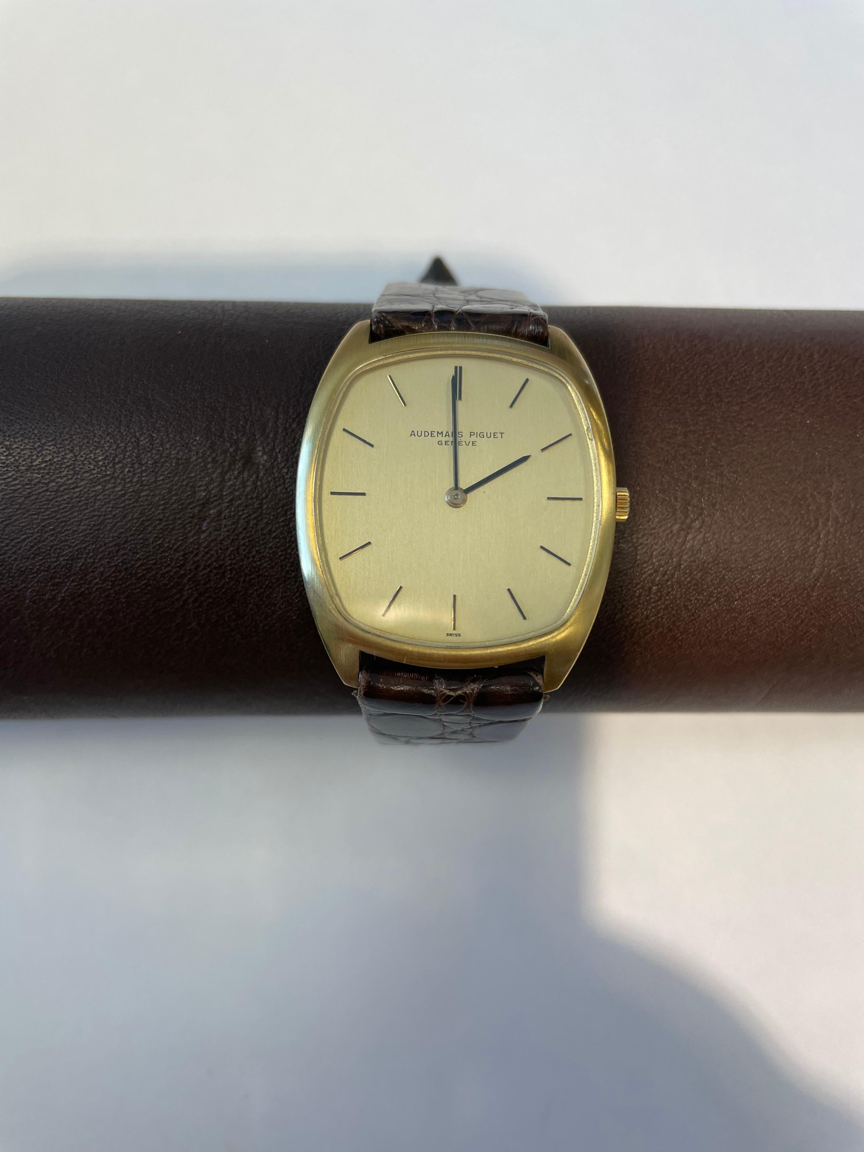 Audemars Piquet 18K yellow gold, cushion shape, satin finish strap watch, gilt dial, stick markers with chocolate brown alligator strap, manual wind.