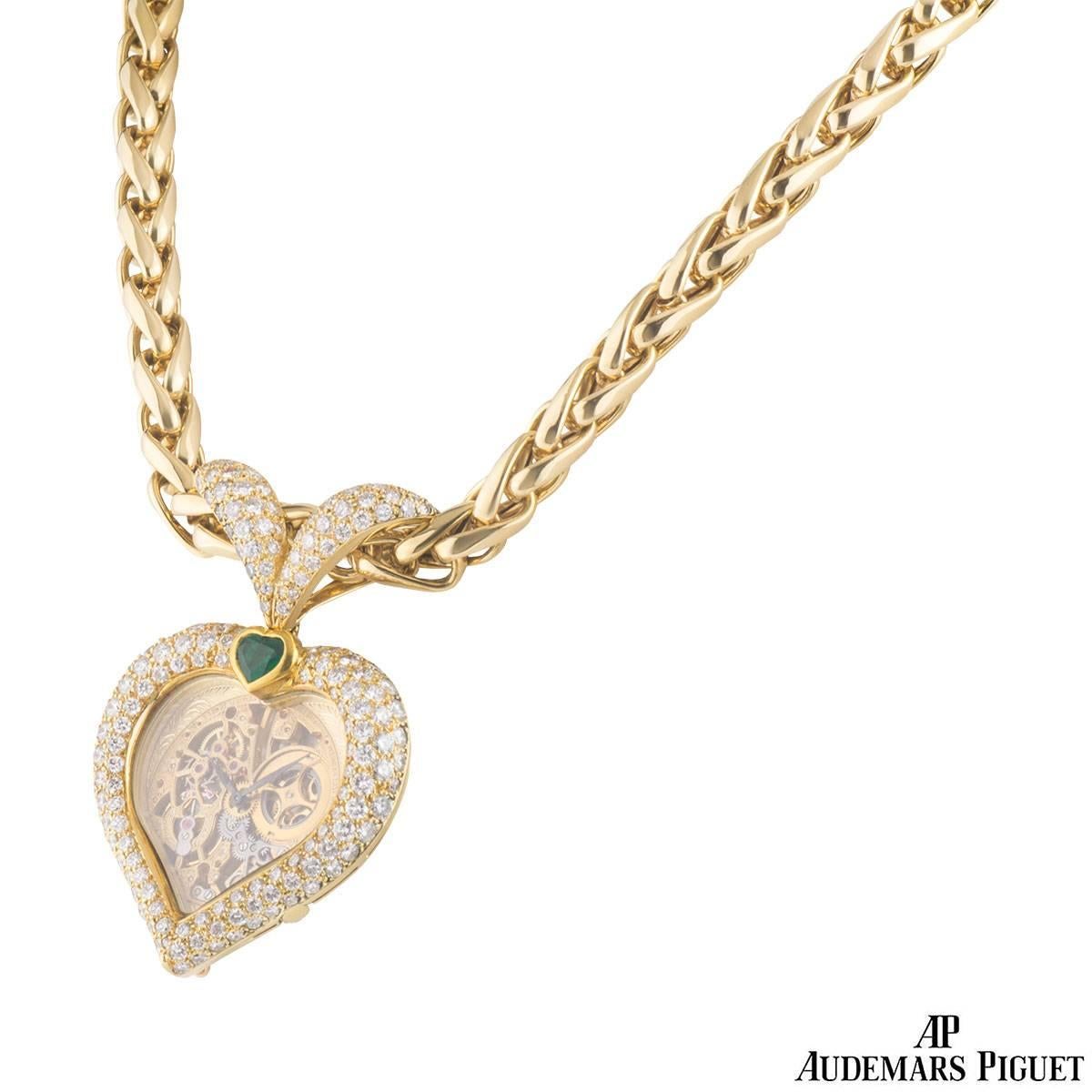 A unique 18k yellow gold diamond and emerald Audemars Piguet pocket watch necklace. The watch comprises of a heart motif with a sapphire glass panel centre. The centre features a skeleton dial and an exhibition caseback. The motif is encrusted in