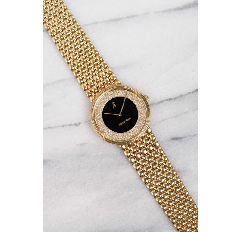An extraordinary and elegant vintage Audemars Piguet crafted entirely in 18k yellow gold, this piece showcases a flawless onyx stone dial—deep, glossy, and perfectly smooth. Surrounding the dial is a brilliant ring of diamonds, precisely set on the