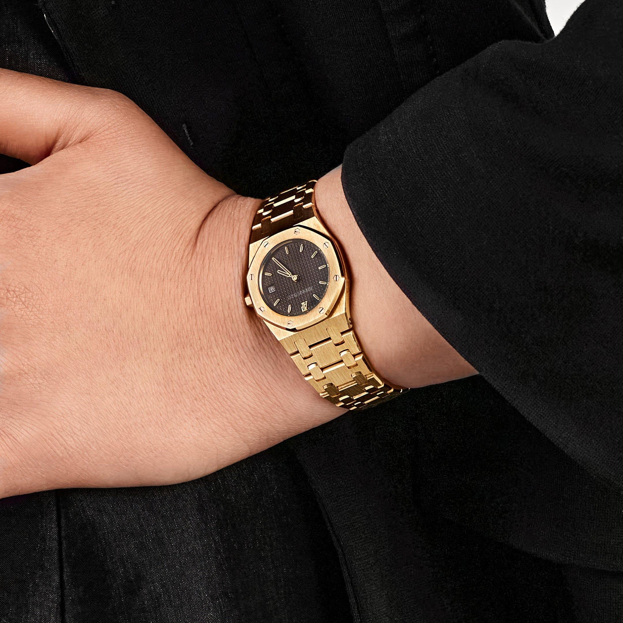 Jewels Aficionado bietet die Audemars Piguet Royal Oak 6007BA 'Ladies' Yellow Gold Grey Dial Quartz an. Sie ist ein raffinierter Ausdruck des ikonischen Designs der Royal Oak, in 26 mm, zugeschnitten auf eine kleinere, elegantere Präsenz am