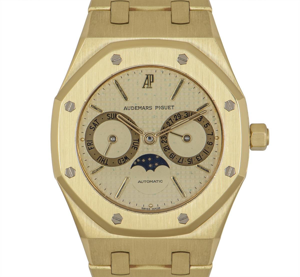 A 36 mm Royal Oak Day-Date Moon Phase in yellow gold by Audemars Piguet. Featuring a champagne waffle dial that has a day, date and moon phase display with the bezel featuring 8 iconic Audemars Piguet screws. The bracelet comes with a concealed