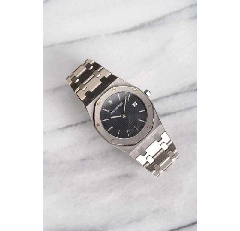 Aquí tienes un Audemars Piguet Royal Oak Quartz de oro blanco de 18 quilates con esfera azul oscuro de la década de 1990. Las medidas incluyen un tamaño de caja de 33 mm y una pulsera integrada. La pulsera se ajusta a una muñeca de hasta 7 pulgadas.