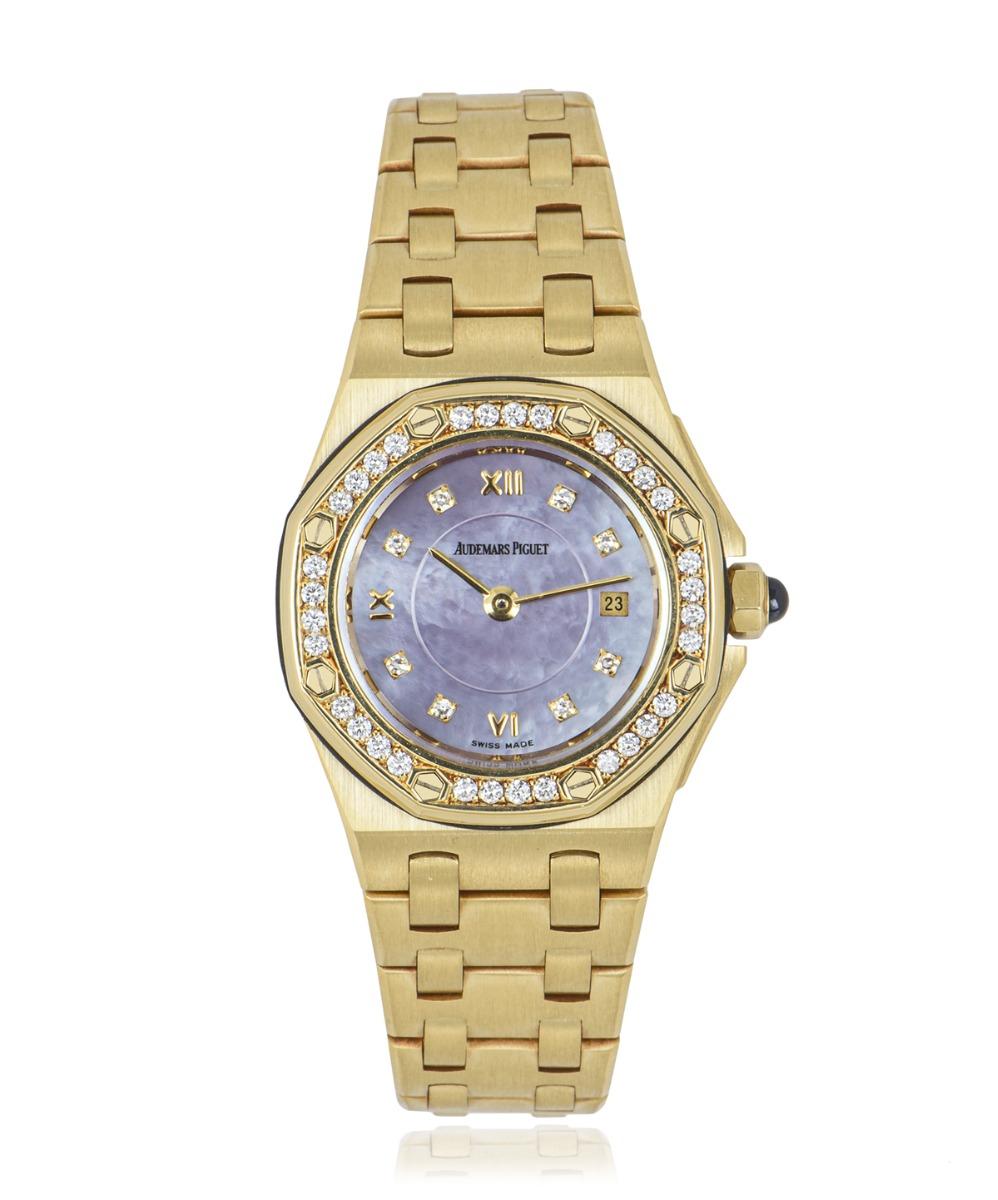 This ladies Royal Oak 27mm wristwatch, in 18k yellow gold by Audemars Piguet, features a mother of pearl dial, with 8 round cut diamond set hour markers, roman numerals VI, XI, XII and a date at 3 o'clock. Complimenting the dial is 32 round cut