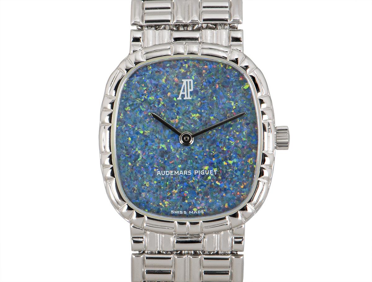 A women's 20mm cocktail dress watch in white gold by Audemars Piguet, featuring a blue opal dial concealed by sapphire glass. The white gold bracelet is equipped with a jewellery style clasp, also in white gold. Fitted with a manual wind