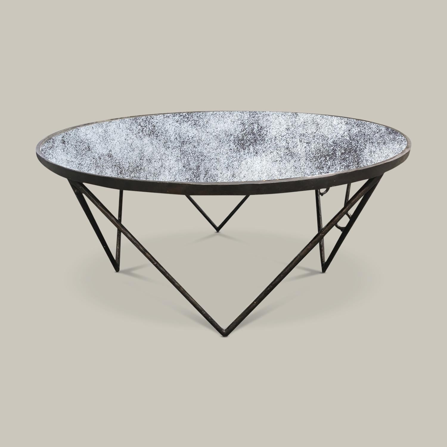 This striking, round cocktail table brings dimension to a room with its reflective top made of antique mirror and an angular, architectural steel base. Handmade by artisans in Vietnam, this piece is a gorgeous addition to a modern living space.