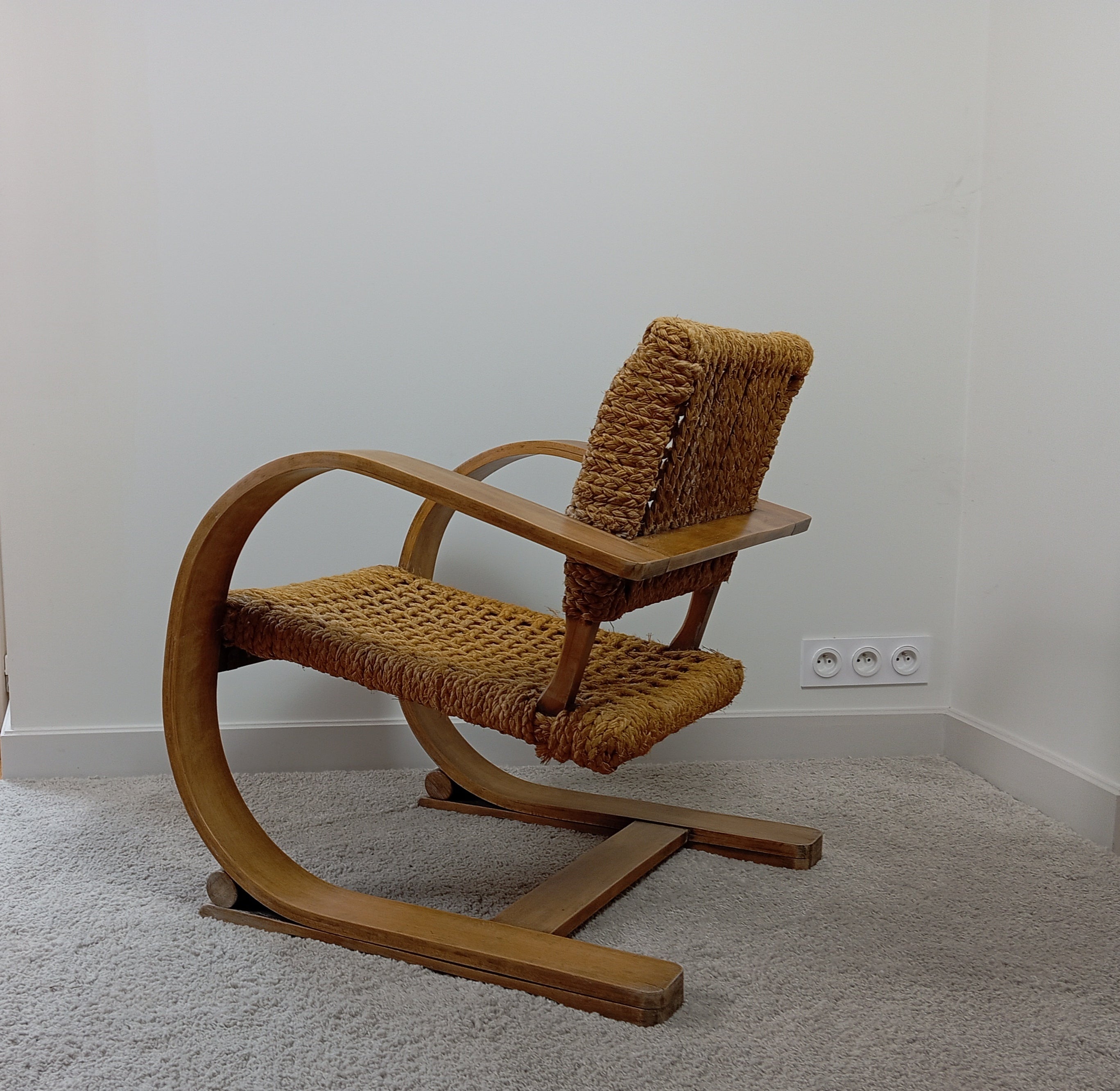 Ce fauteuil a été dessiné par les designers Adrien Audoux et Frida Minet dans les années 50, puis édité par Vibo Vesoul. Il est doté d'une structure incurvée en hêtre stratifié et d'une assise et d'un dossier en corde de chanvre tressée. 

Ce modèle