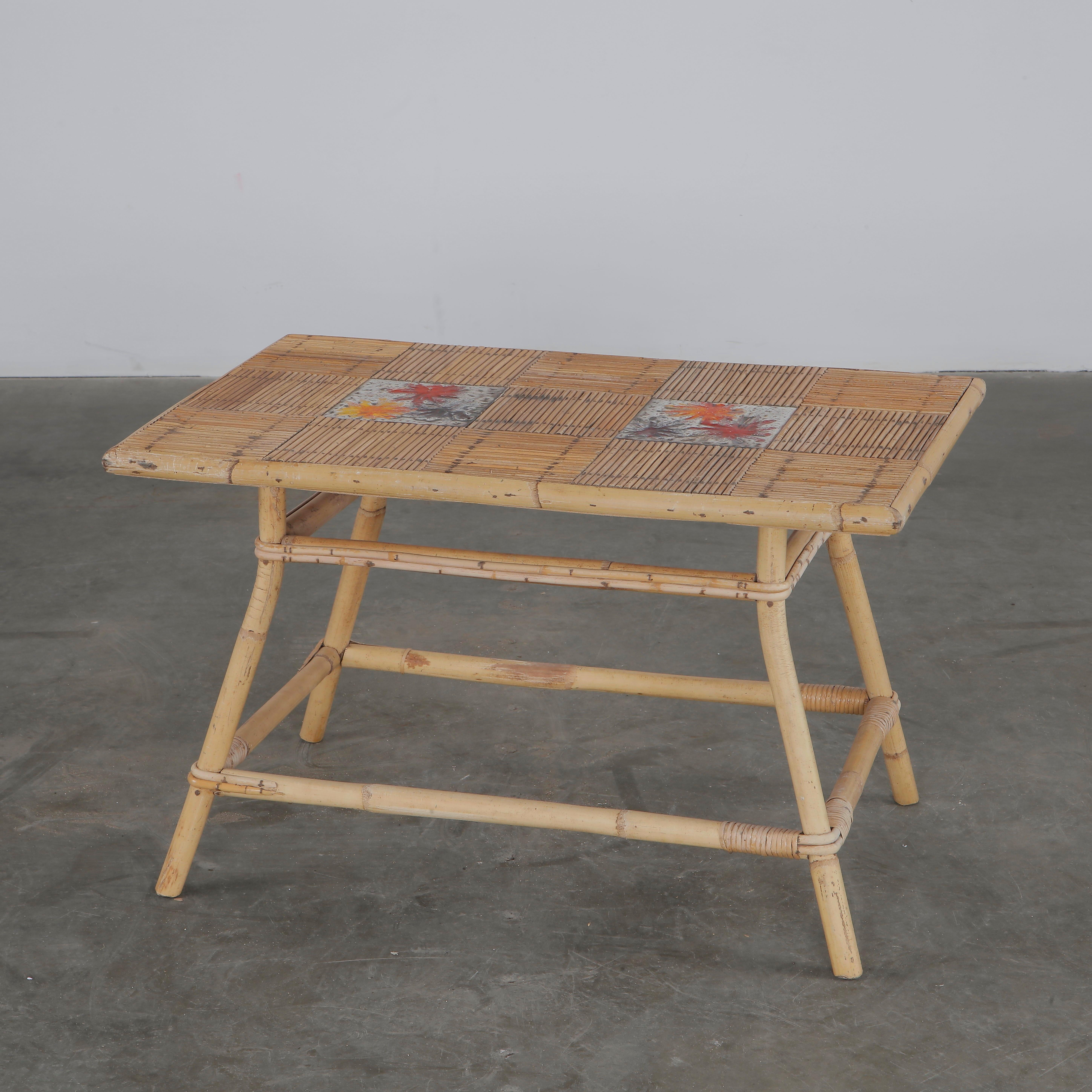 Charming rattan and tile coffee table by Audoux-Minet for Roger Capron, featuring hand-painted floral ceramic inserts. France, 1950s. Height: 19 in. Width: 30 in. Depth: 19 in.