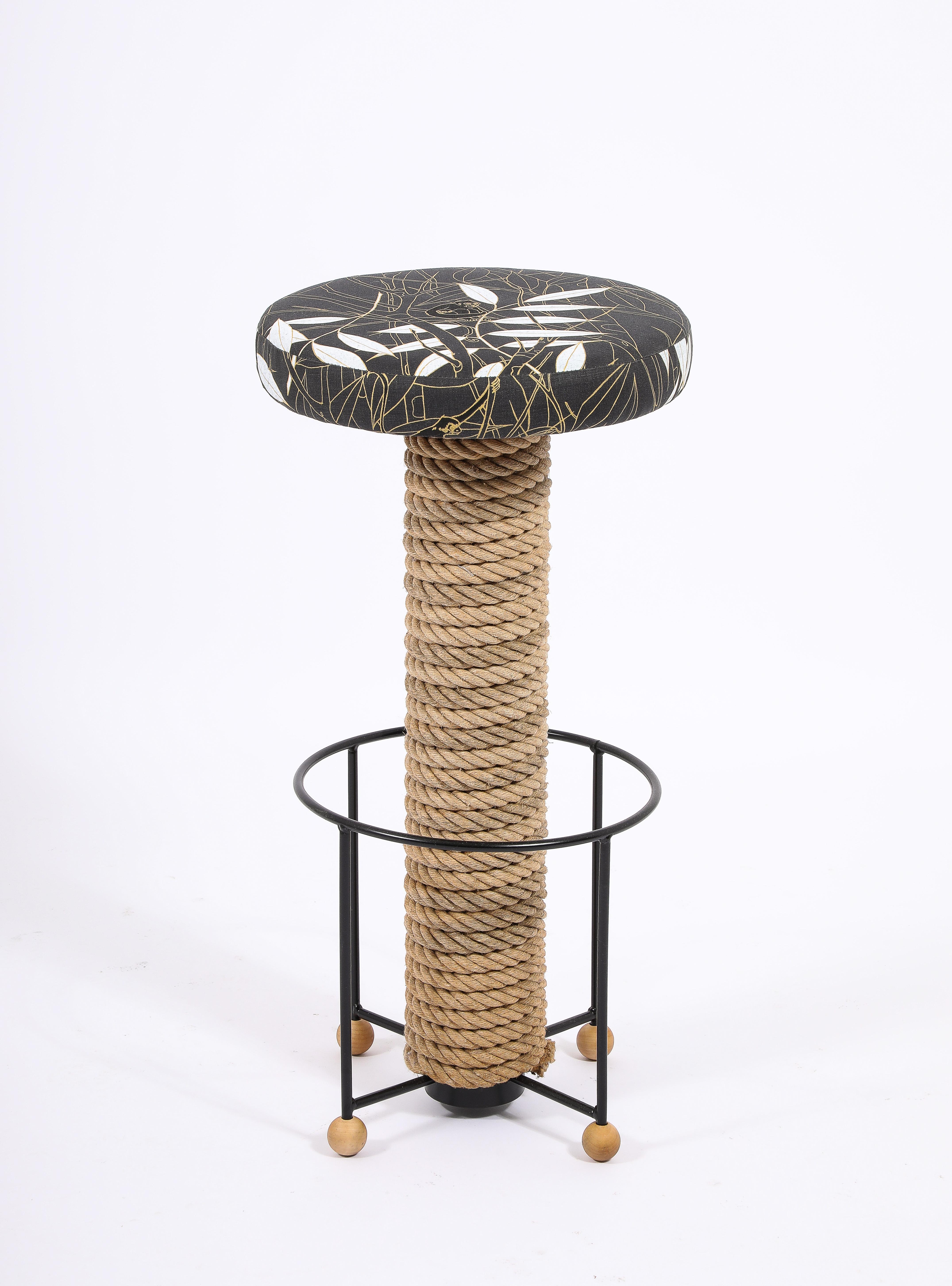Barstools in wrought iron, the stem wrapped in thick natural rope on wooden ball feet.

