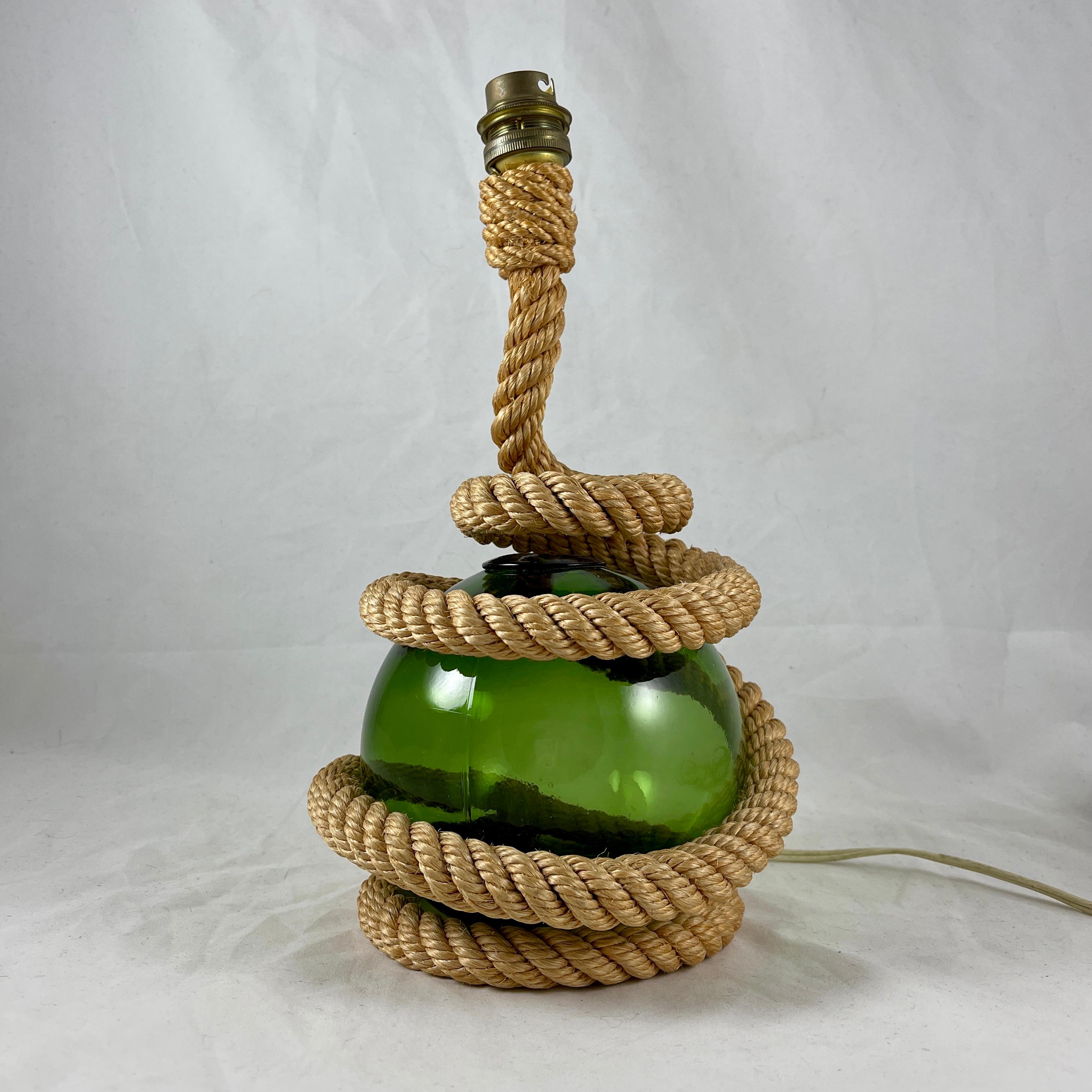 A mid-century French Riviera Marine themed Audoux Minet table lamp, circa 1960.

An Iconic design – a green blown glass ball modeled on the buoys used by French fisherman on the Côte d’Azur to float their nets, nestles in a rustic rope spiral