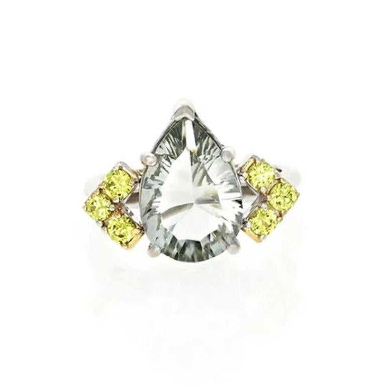 The Audree Ring is a timeless piece of elegance, featuring a captivating pear-shaped green amethyst as its centerpiece. Crafted in 14kt white gold, this size 4.5 ring is accented with six vibrant 2.5mm yellow sapphires, adding a touch of warmth and