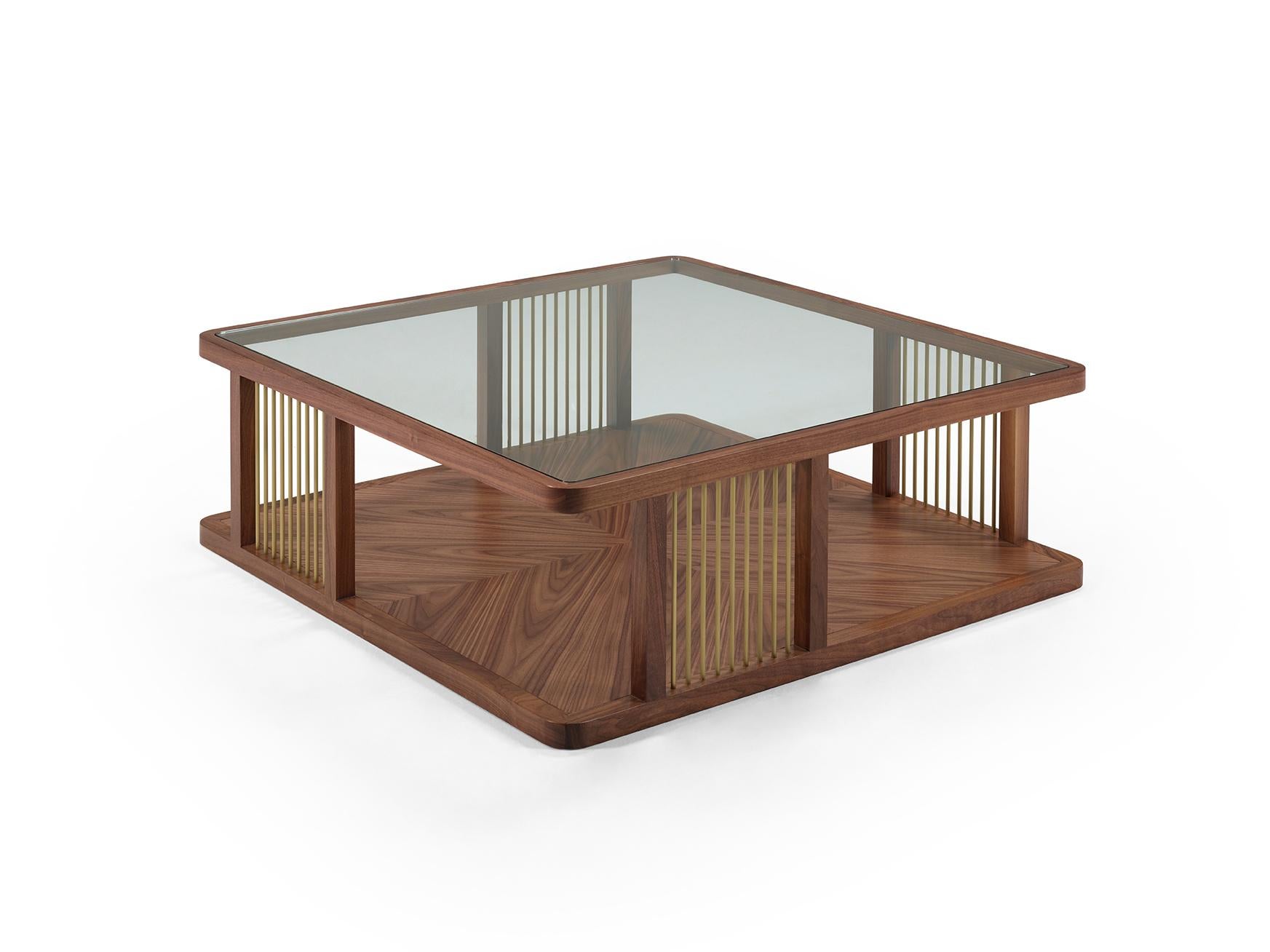 AUDREY is a notable coffee table. The tempered glass top allows the look to the well-gauged base in wood, featuring a play of shapes. The structure is graced by the metal details, in brass or stainless steel, keeping the balanced design. Audrey is